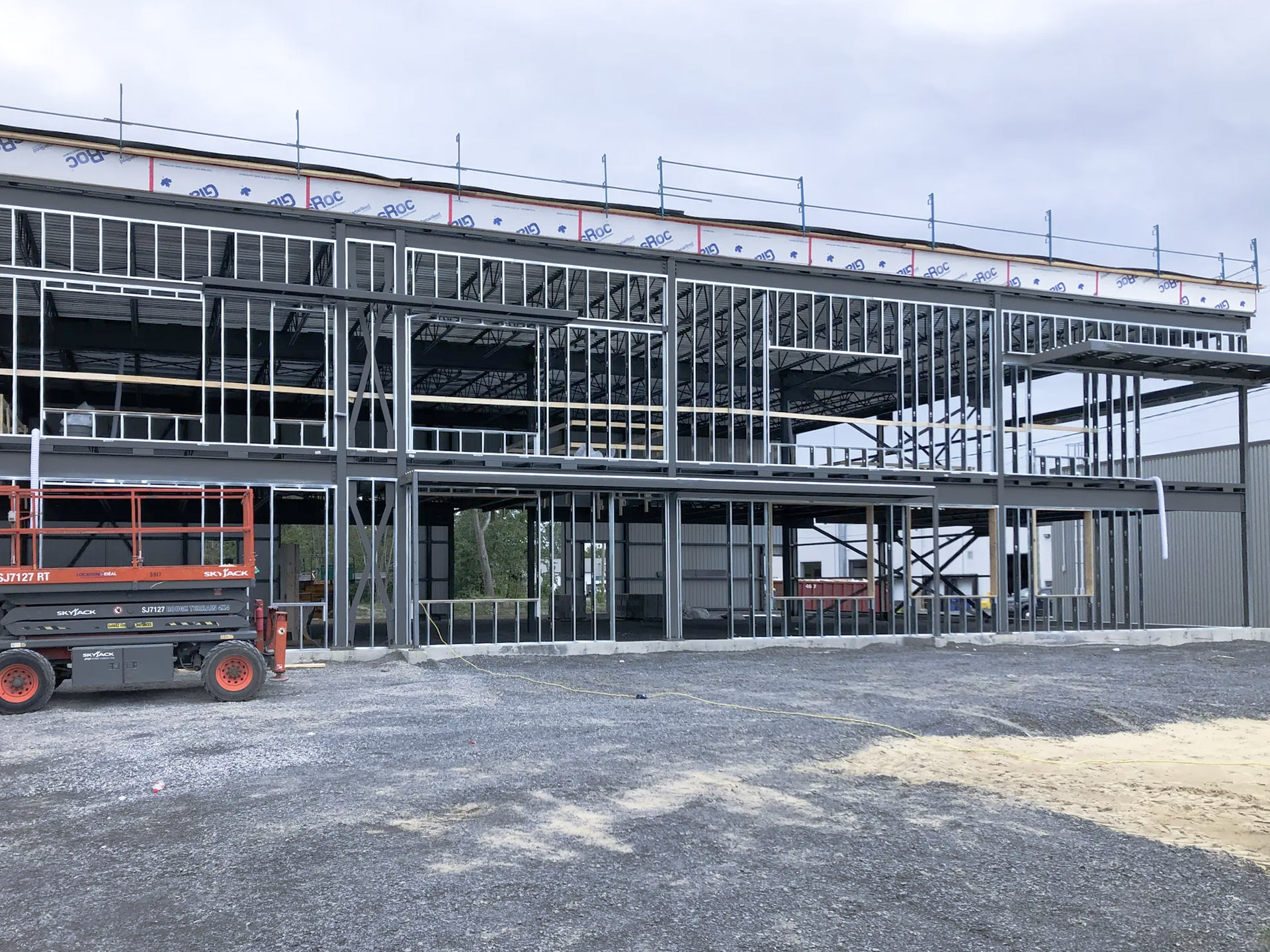 Construction d’un bâtiment commercial à ossature d’acier avec échafaudages et nacelle élévatrice sur chantier
