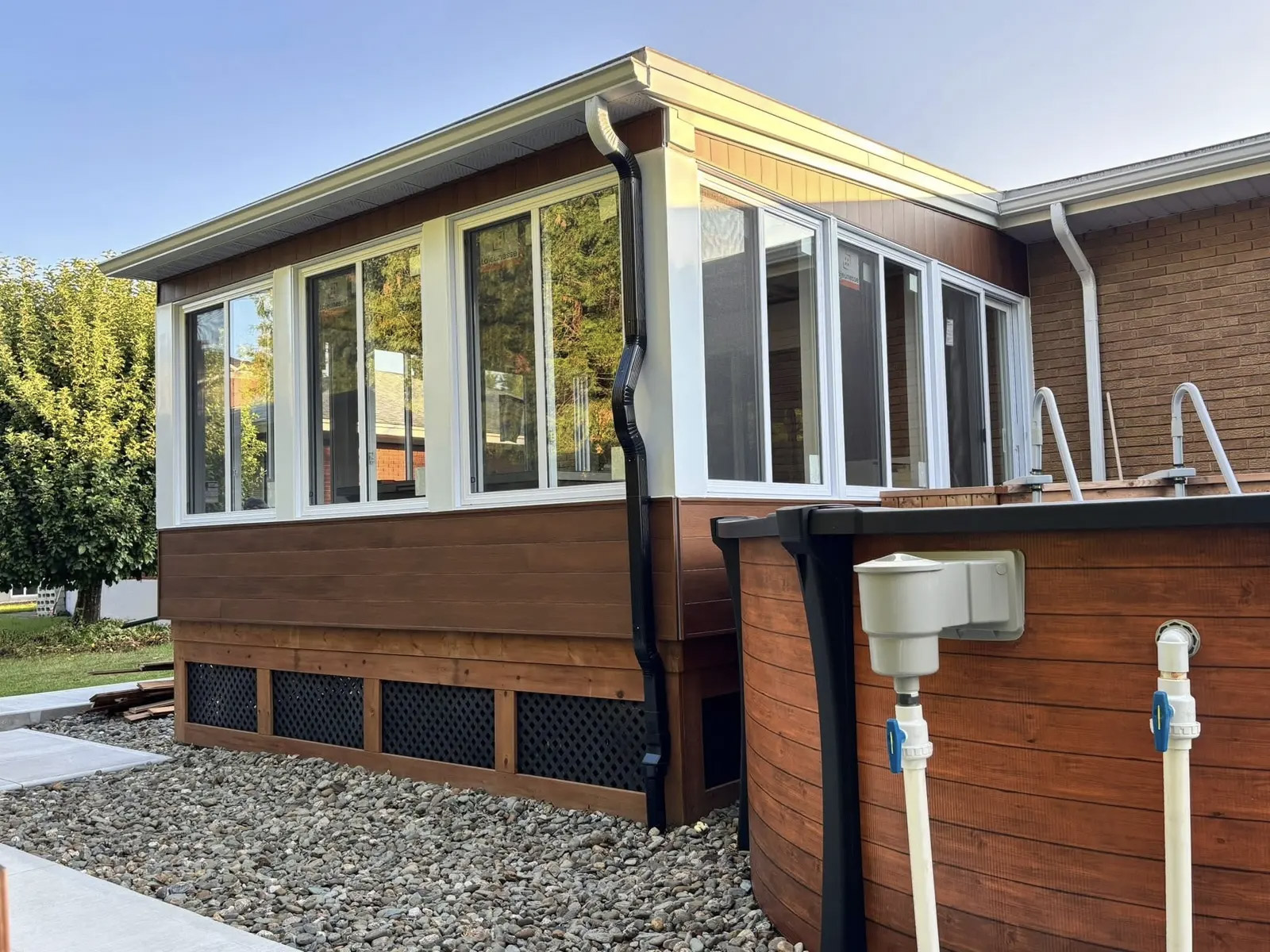 Solarium résidentiel en bois avec grandes fenêtres blanches et spa extérieur intégré