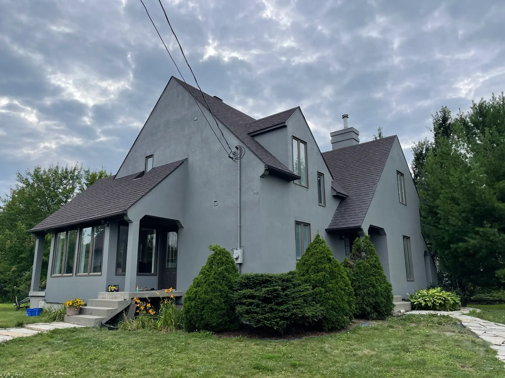 &nbsp;Maison traditionnelle rénovée avec revêtement acrylique gris, toiture en pente et aménagement paysager