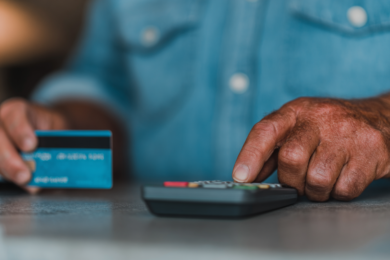 Close-up of a hand inserting a bank card PIN into a payment terminal