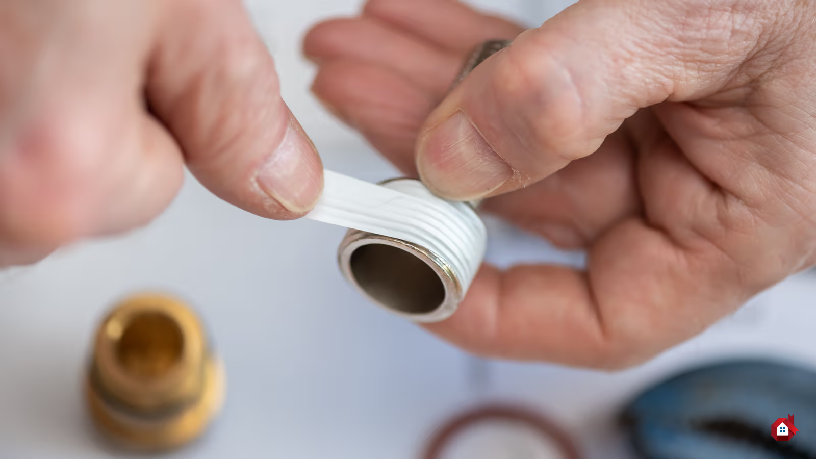 Mains appliquant du ruban de plomberie blanc sur le filetage d’un tuyau métallique pour assurer l’étanchéité d’un raccord.