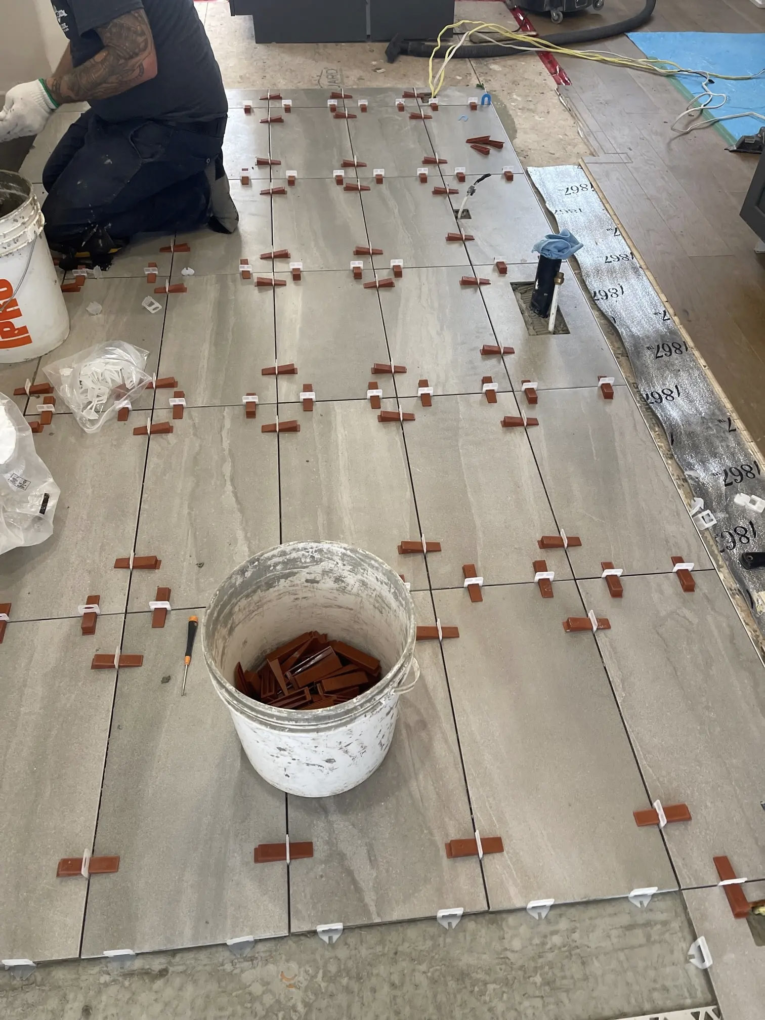 Pose de grands carreaux avec croisillons, système de nivellement et outils de chantier.