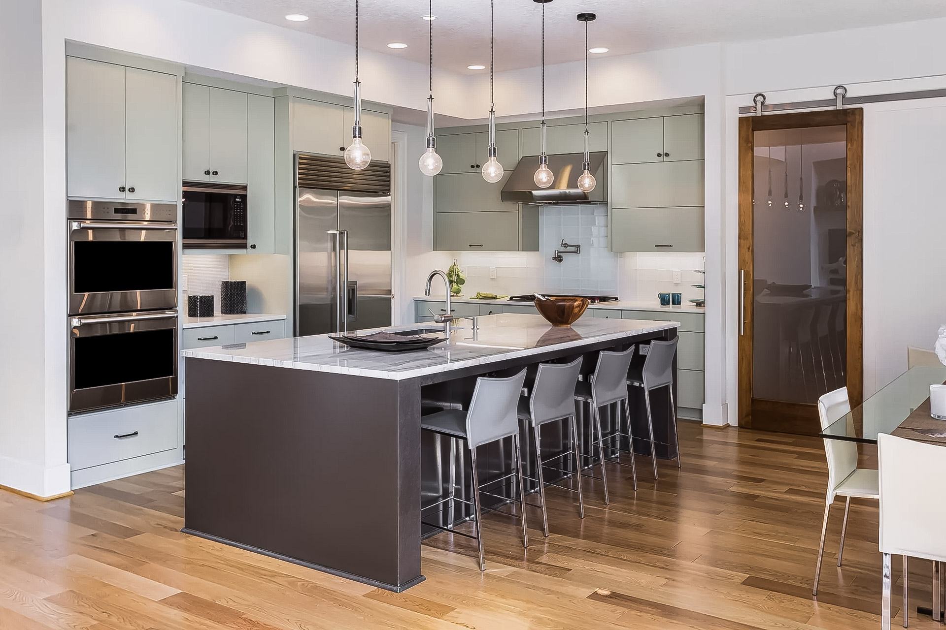 Cuisine moderne avec îlot central, comptoir en marbre et électroménagers en acier inoxydable.