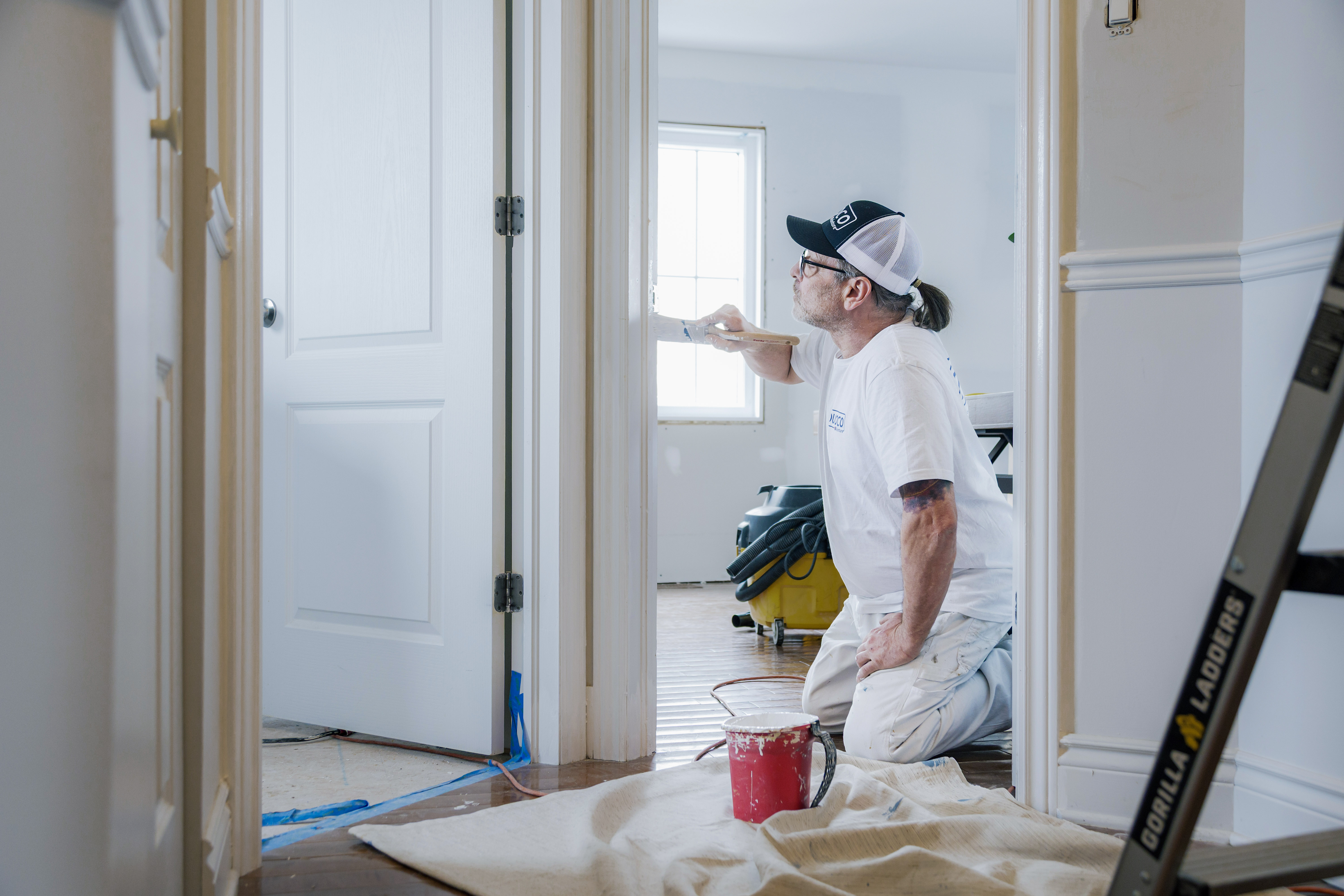 Peintre professionnel appliquant de la peinture blanche sur les murs d'une maison en rénovation intérieure