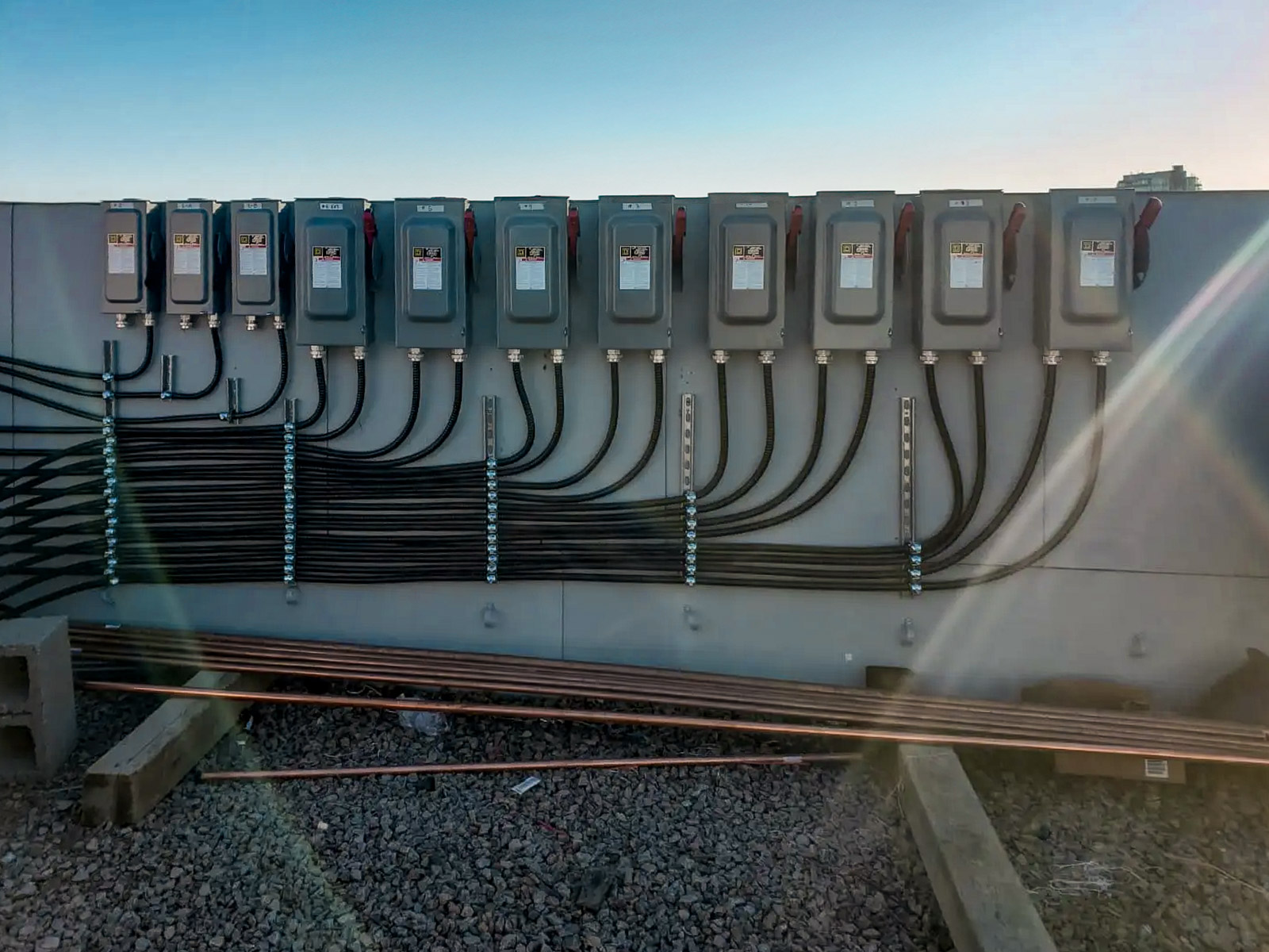 Row of industrial circuit breaker boxes mounted on a panel with organized wiring at an outdoor site