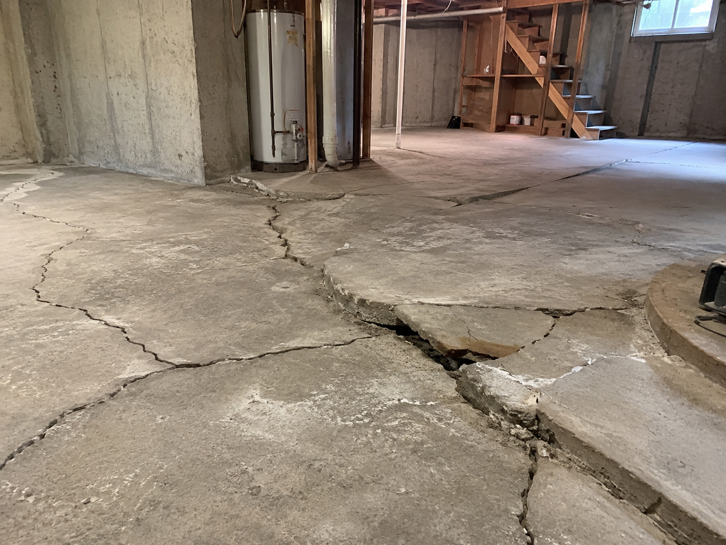 Un plancher de sous-sol présentant de fortes fissures et un soulèvement du béton, probablement causés par l’expansion de la pyrite sous la dalle.