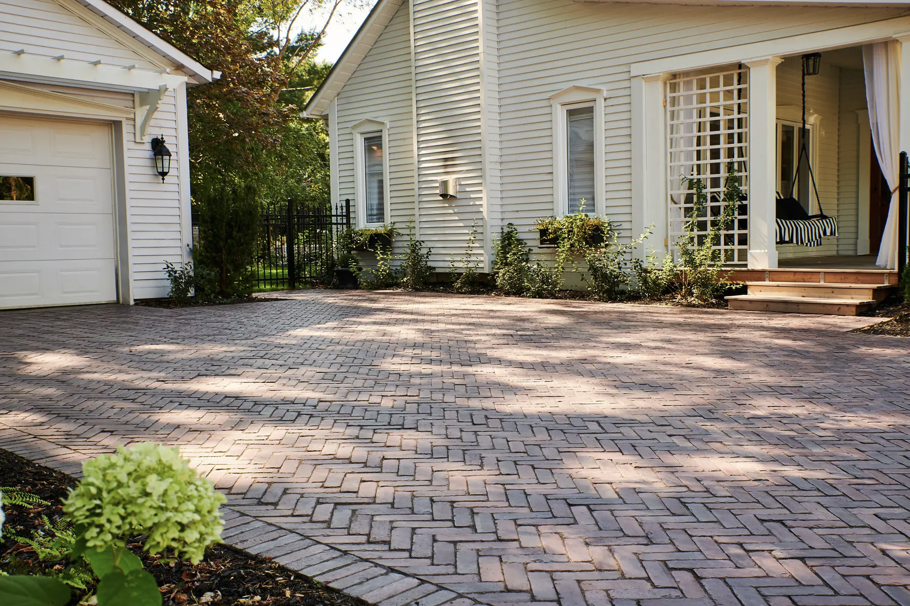 Entrée de maison en pavé-uni de style brique avec aménagement paysager devant une résidence blanche