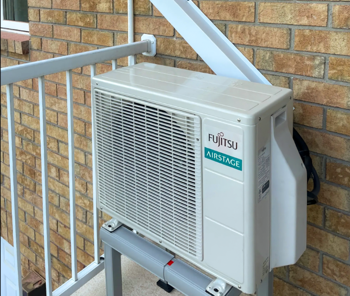 Fujitsu AIRSTAGE outdoor unit installed on a metal support against a brick wall