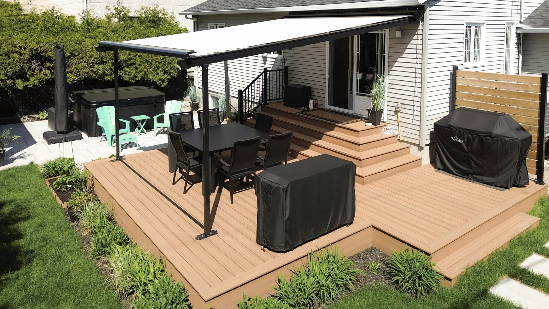 Terrasse en composite avec auvent rétractable, coin repas et spa extérieur.