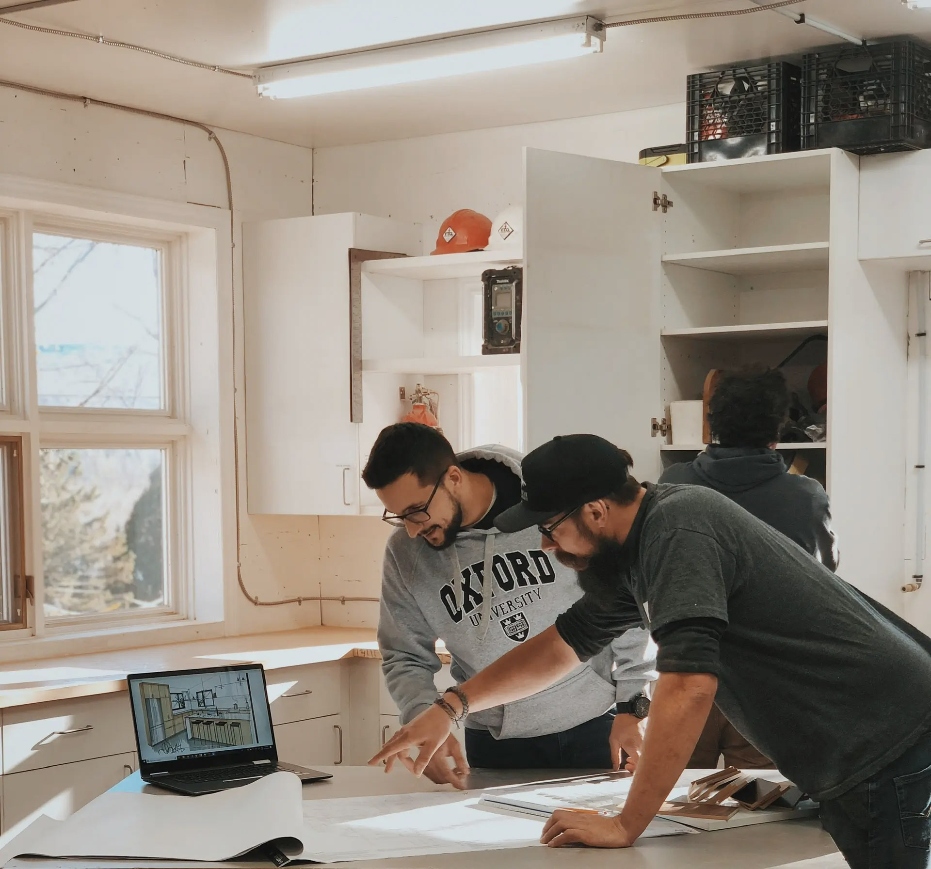 Des professionnels collaborent dans un atelier sur la conception d'un projet architectural avec plans et ordinateur portable.