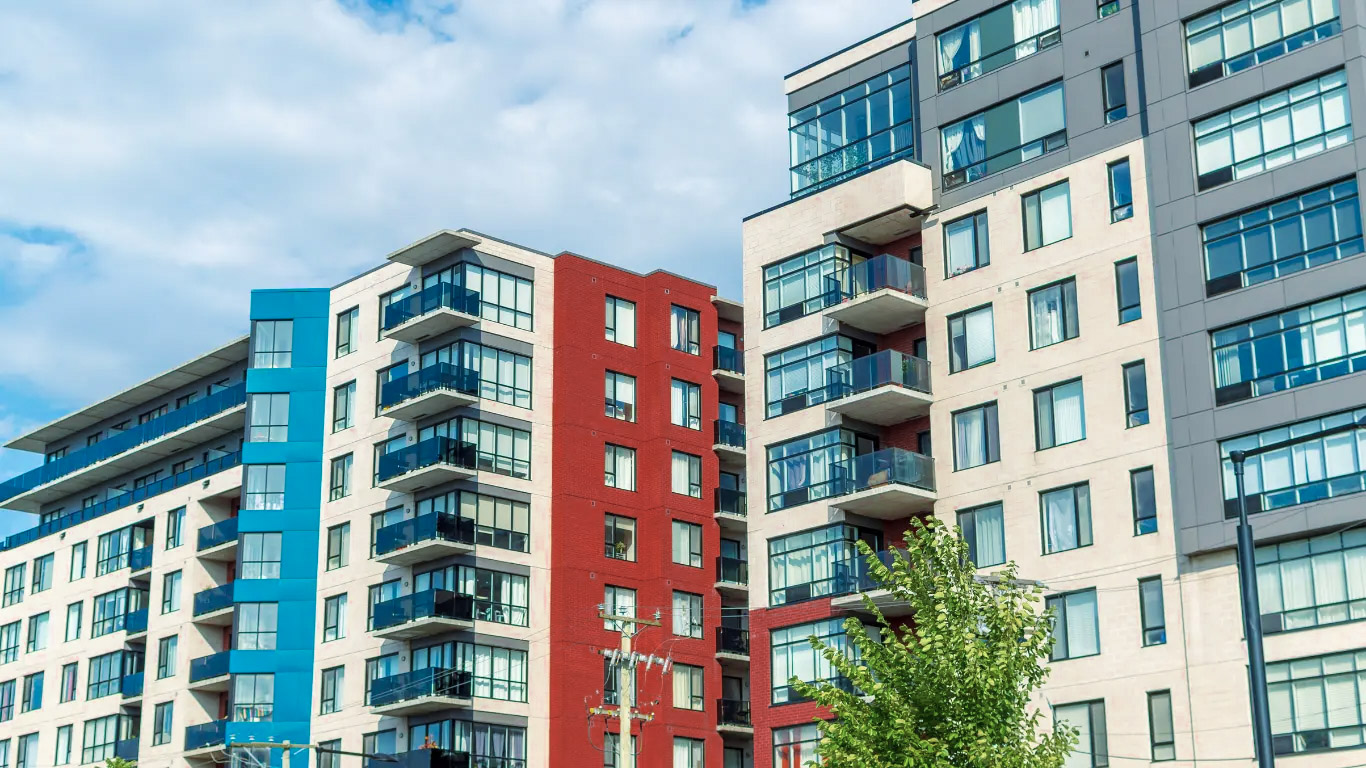 Modern residential apartment buildings with glass balconies, large windows and colorful urban facades
