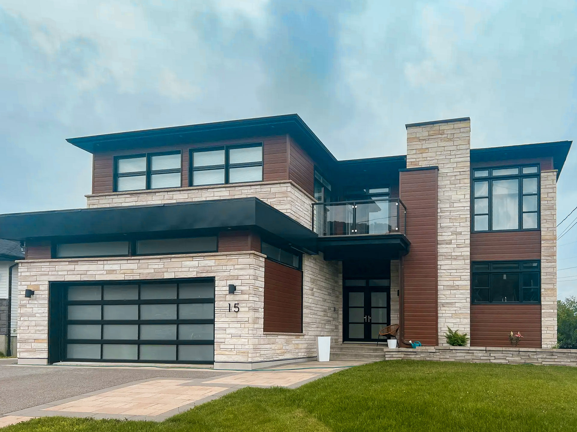 Contemporary two-story house with Suretouch stone and wood panel cladding, glass garage and glass balcony