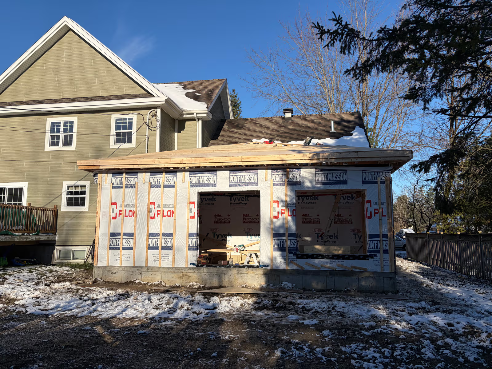 Home extension under construction with wooden framing, house wrap and concrete foundation