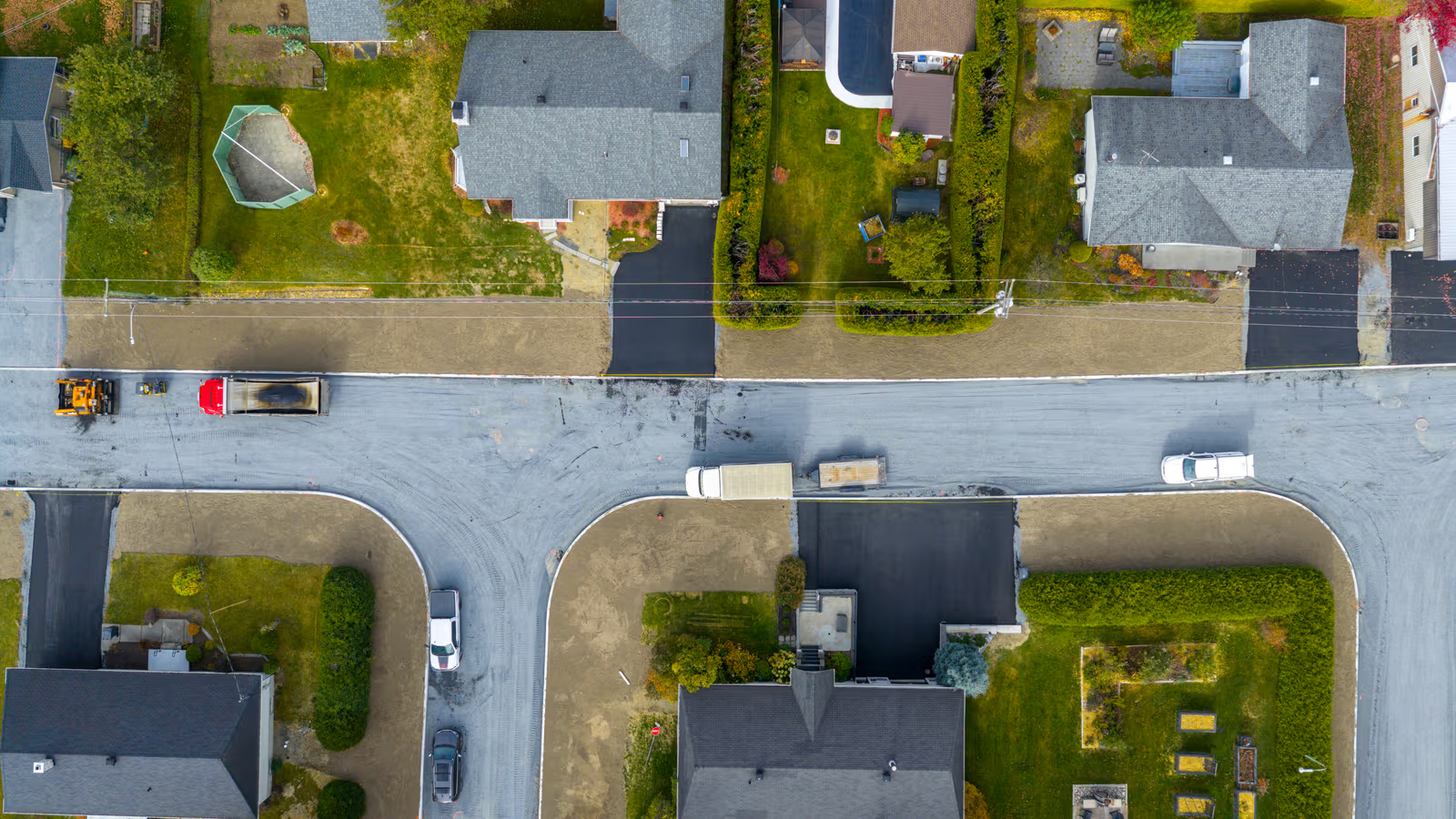 Aerial view of a residential neighbourhood with road paving work, houses, streets and landscaping