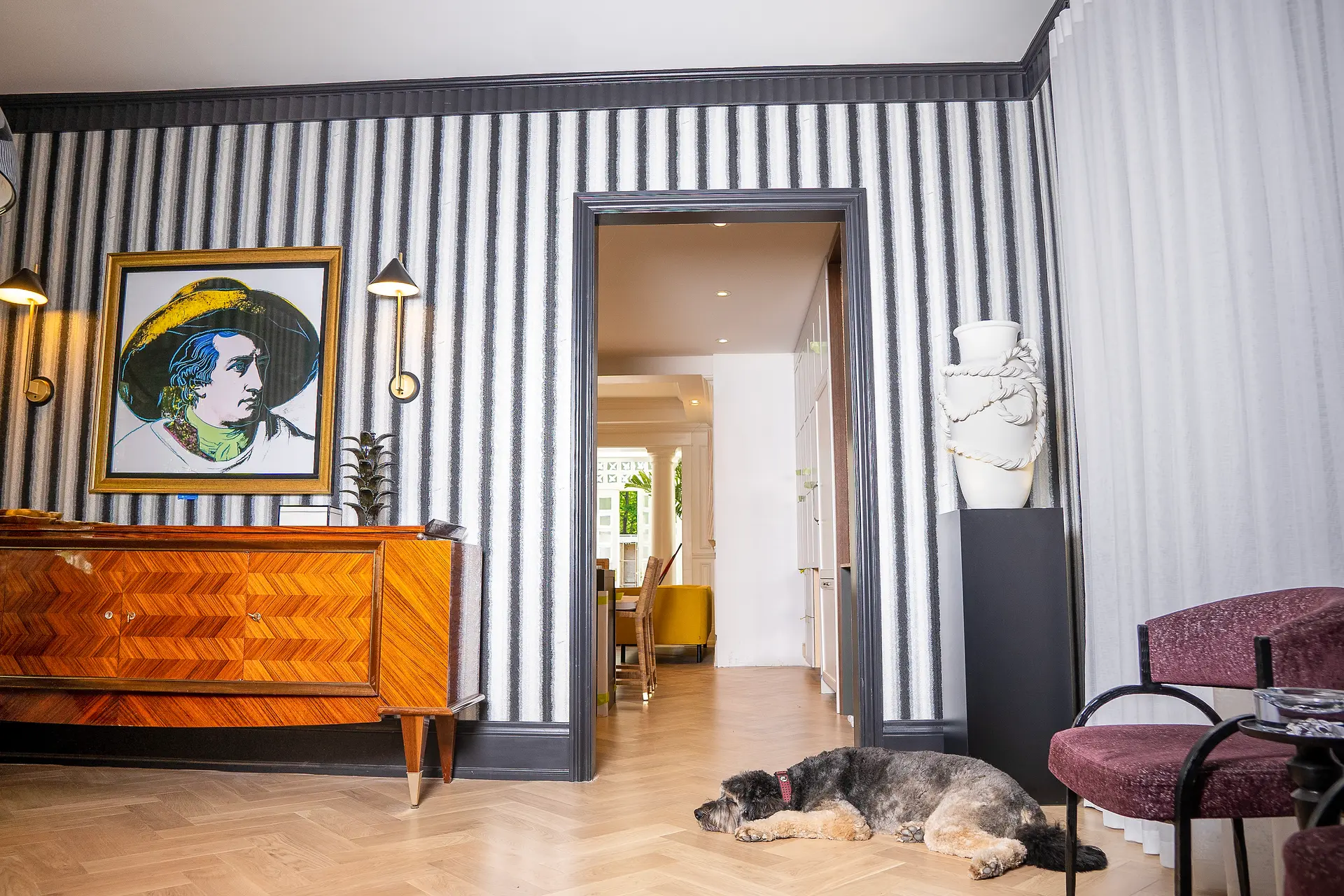Intérieur raffiné avec papier peint rayé, meuble design en bois, et parquet en chevron.