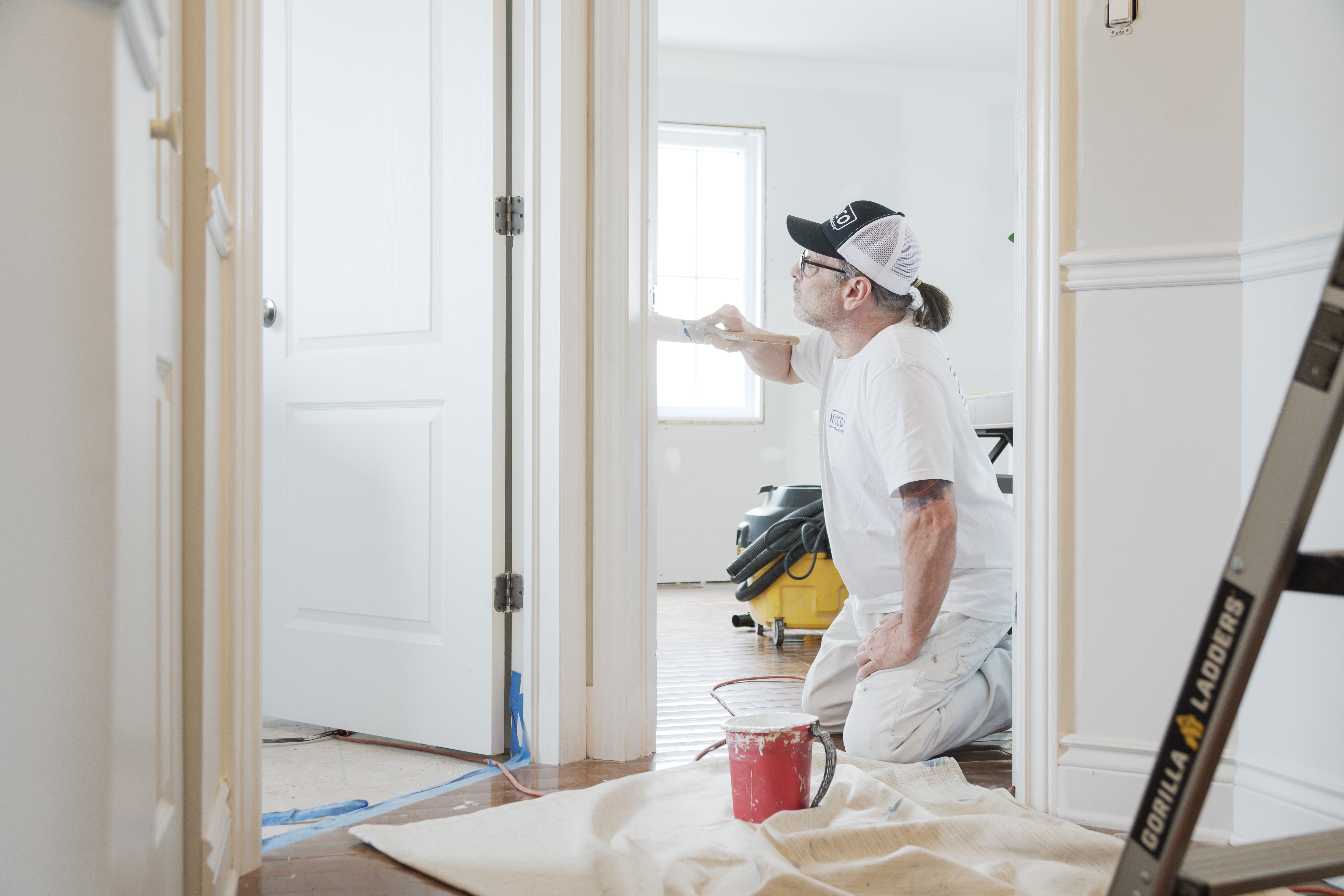 Professional painter applying white paint to the walls of a home undergoing interior renovation