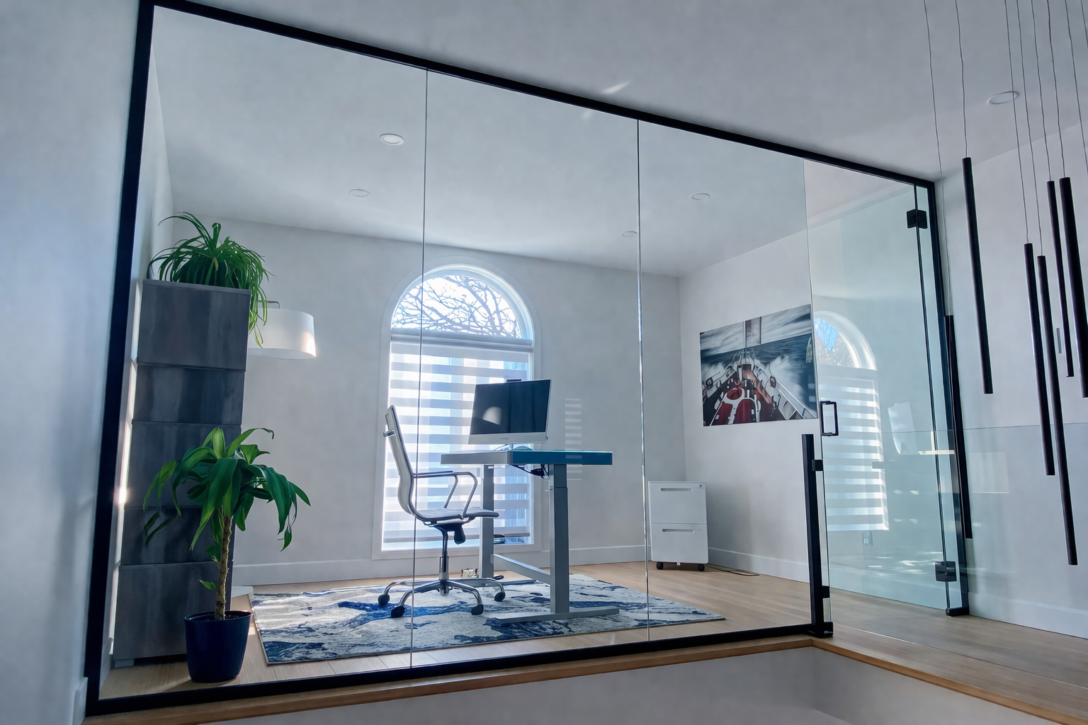 Bureau moderne vitré avec cloison en verre, cadre noir, bureau assis-debout, plantes et grande fenêtre arquée