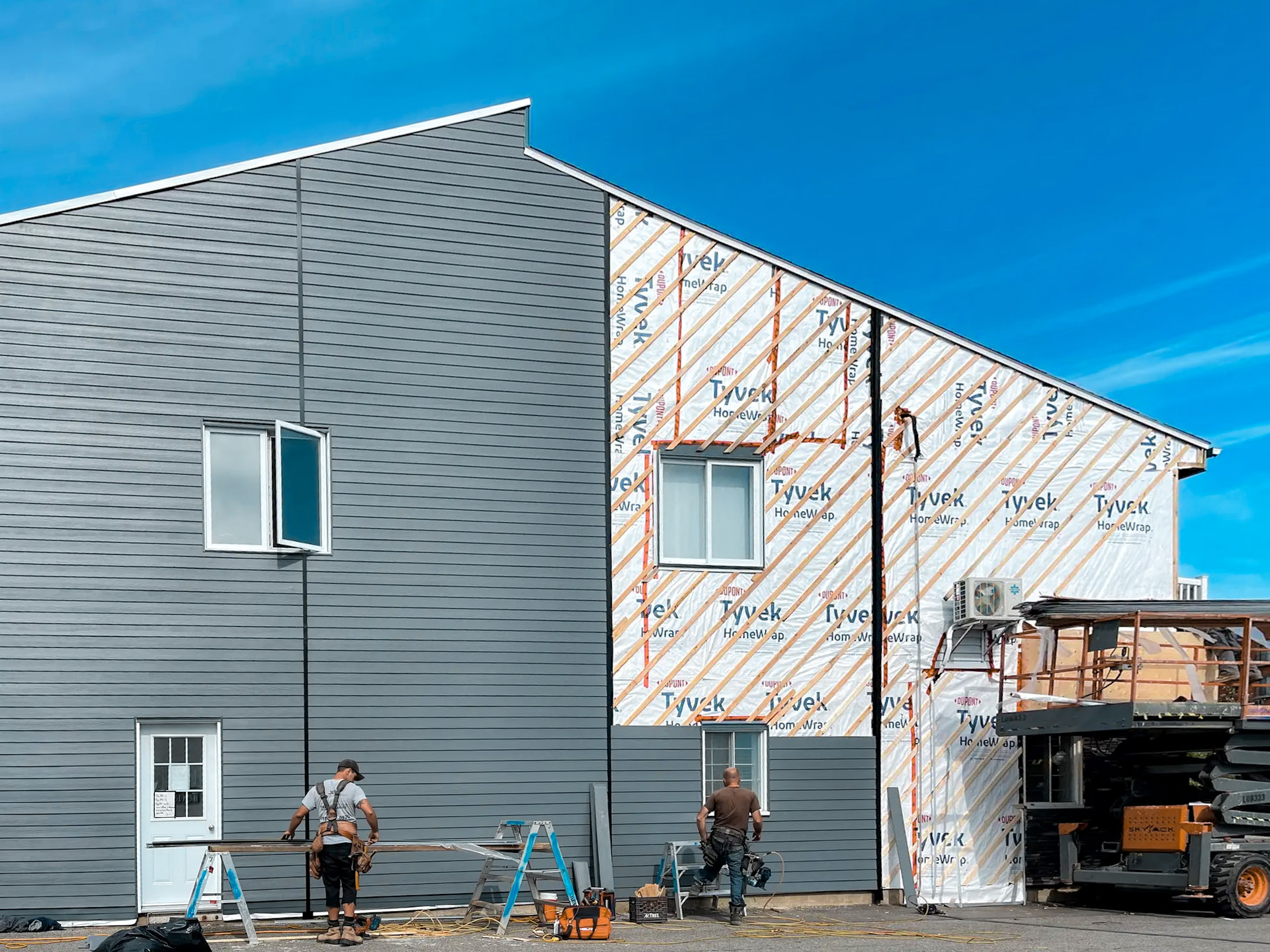 Pose de revêtement extérieur sur une maison avec pare-intempéries Tyvek et finition en panneaux horizontaux gris