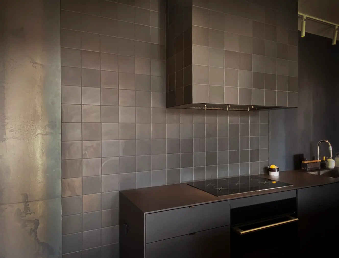 Modern kitchen with matte black ceramic backsplash and range hood, minimalist countertop, and built-in appliances