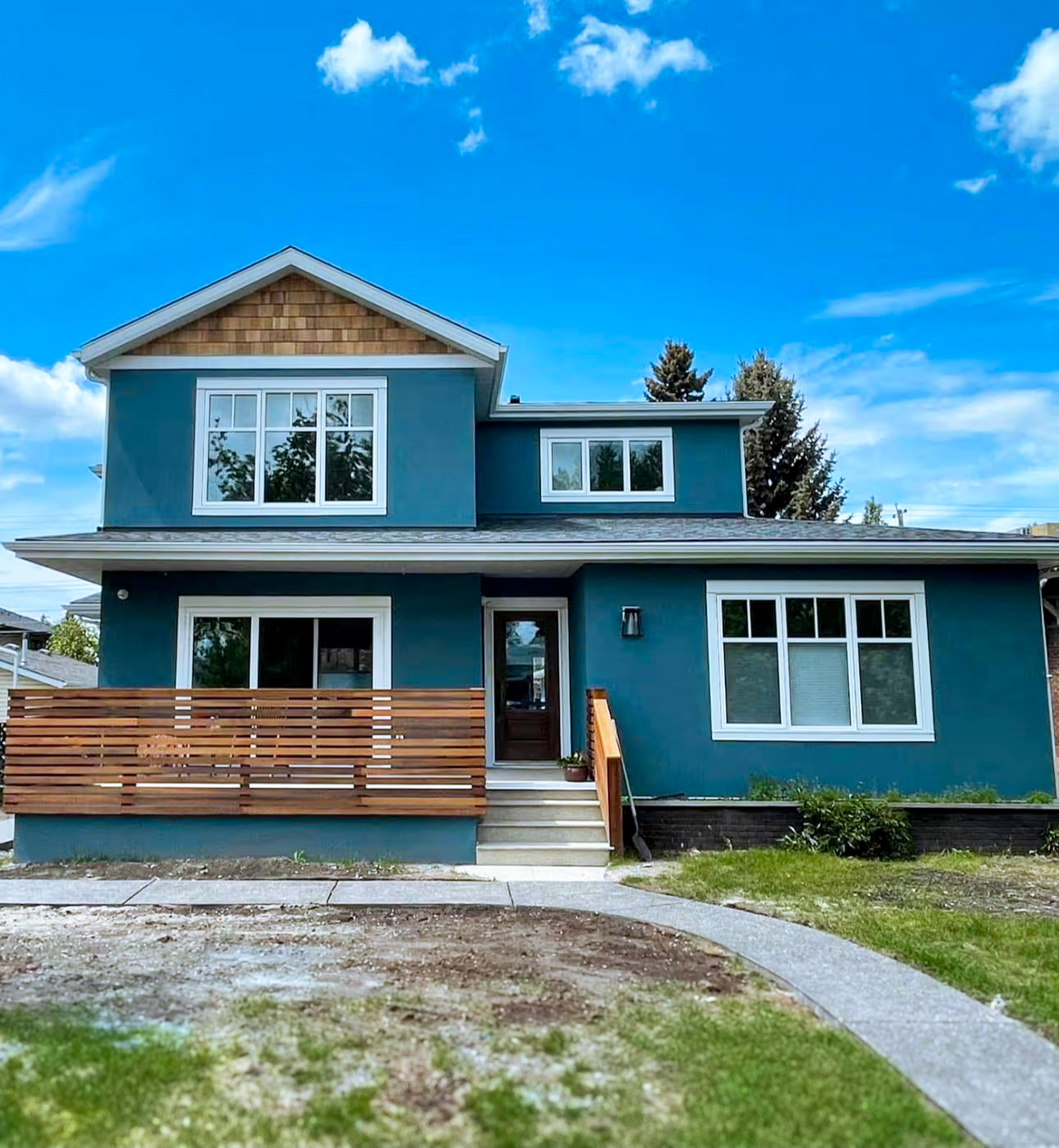 Modern blue house with uniform exterior cladding, wooden gable accents and a balcony with wooden railings