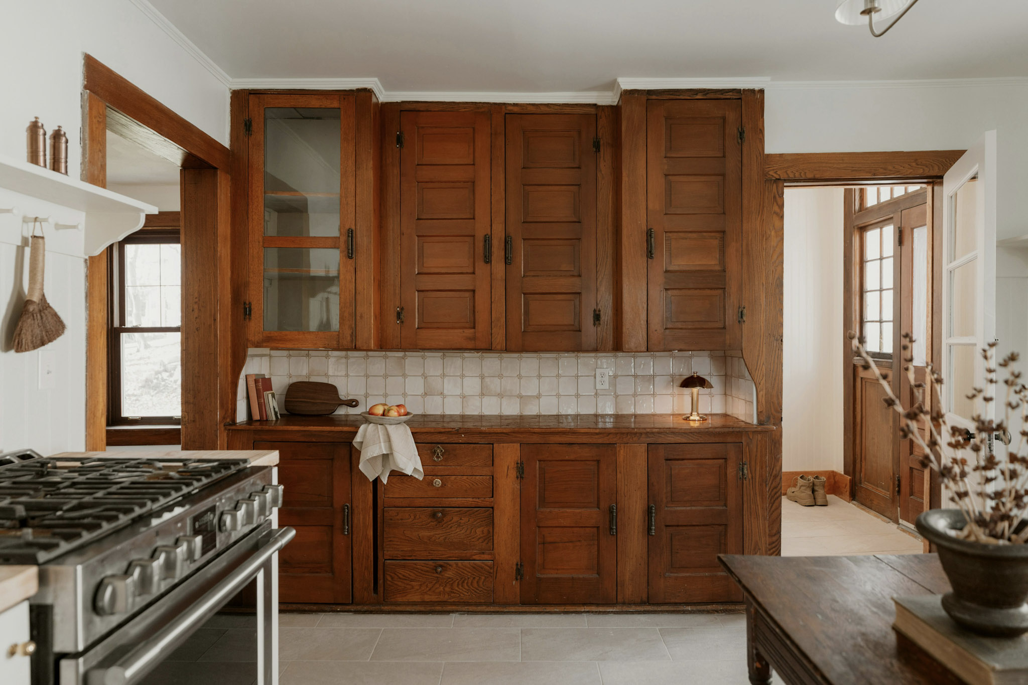 Cuisine traditionnelle avec armoires en bois, dosseret en carreaux blancs et cuisinière professionnelle.