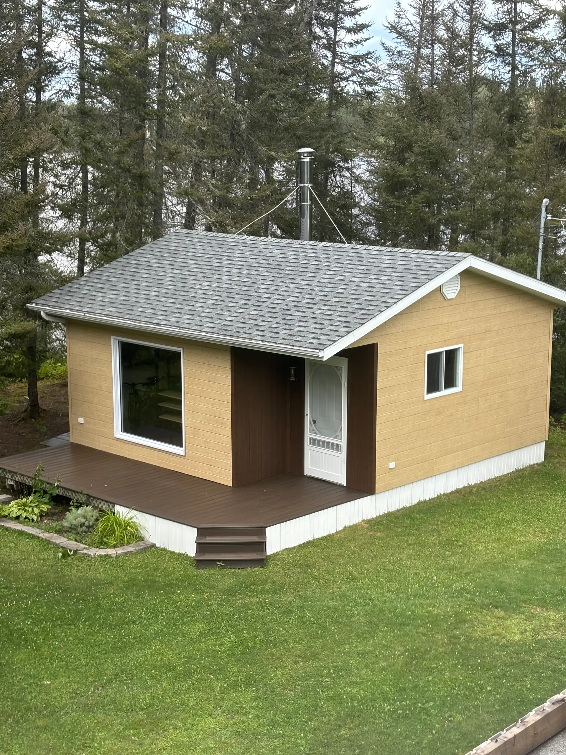 Maison unifamiliale rénovée avec revêtement extérieur moderne, toiture en bardeaux, fenêtres et grande terrasse en composite