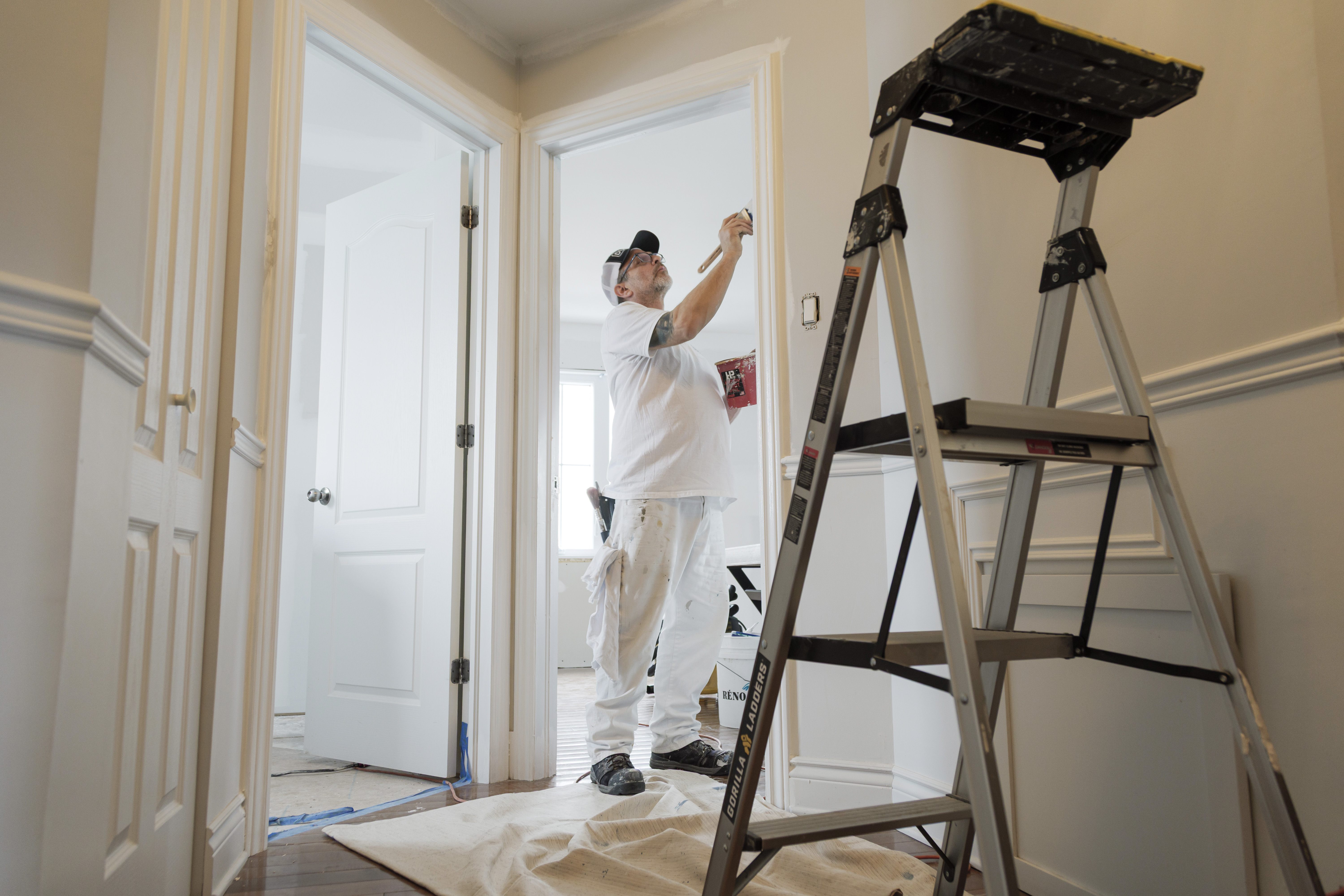 Professional painter applying white paint to interior trim in a residential home
