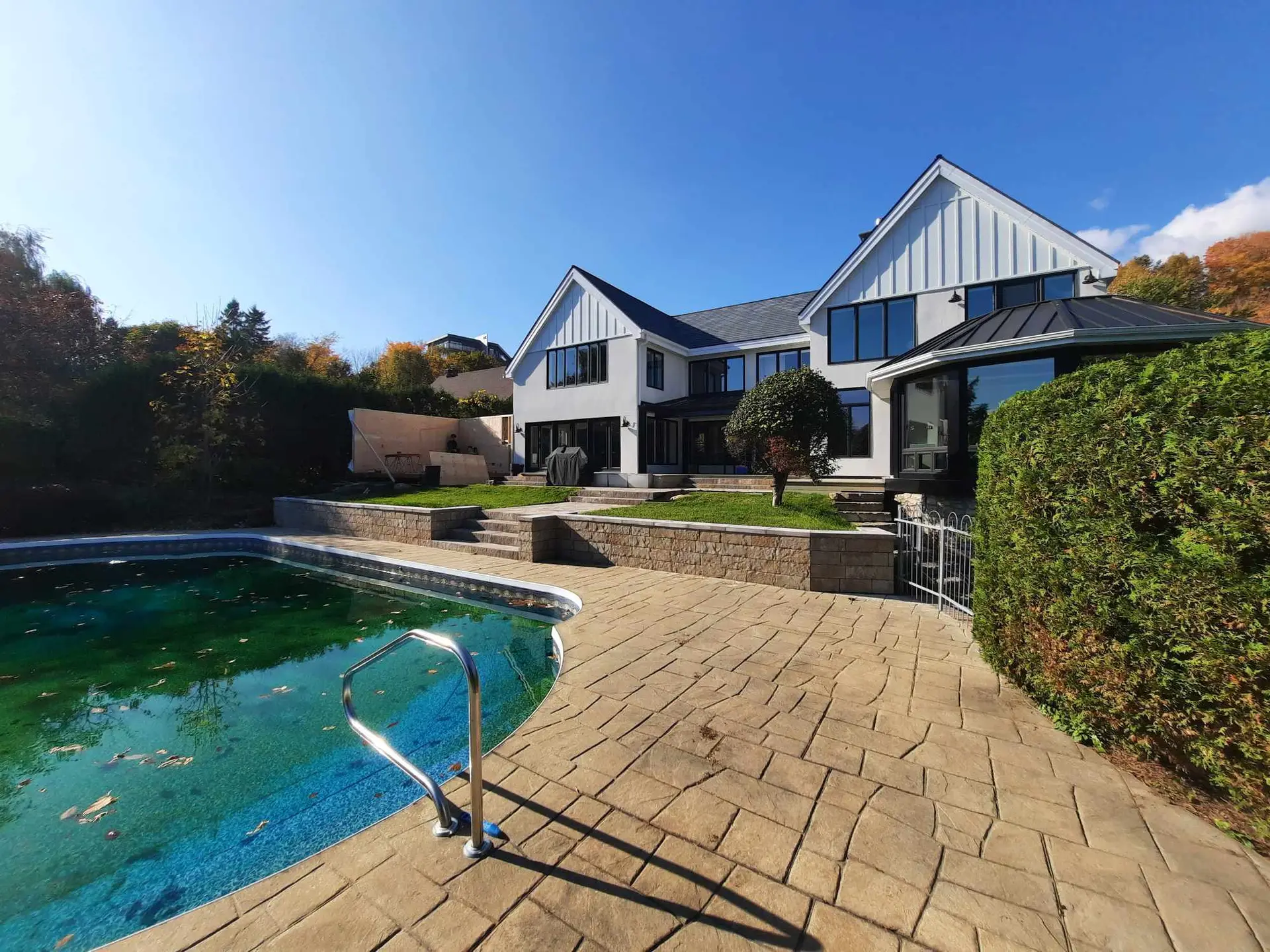 Residential backyard with in-ground pool, stamped concrete patio and landscaping