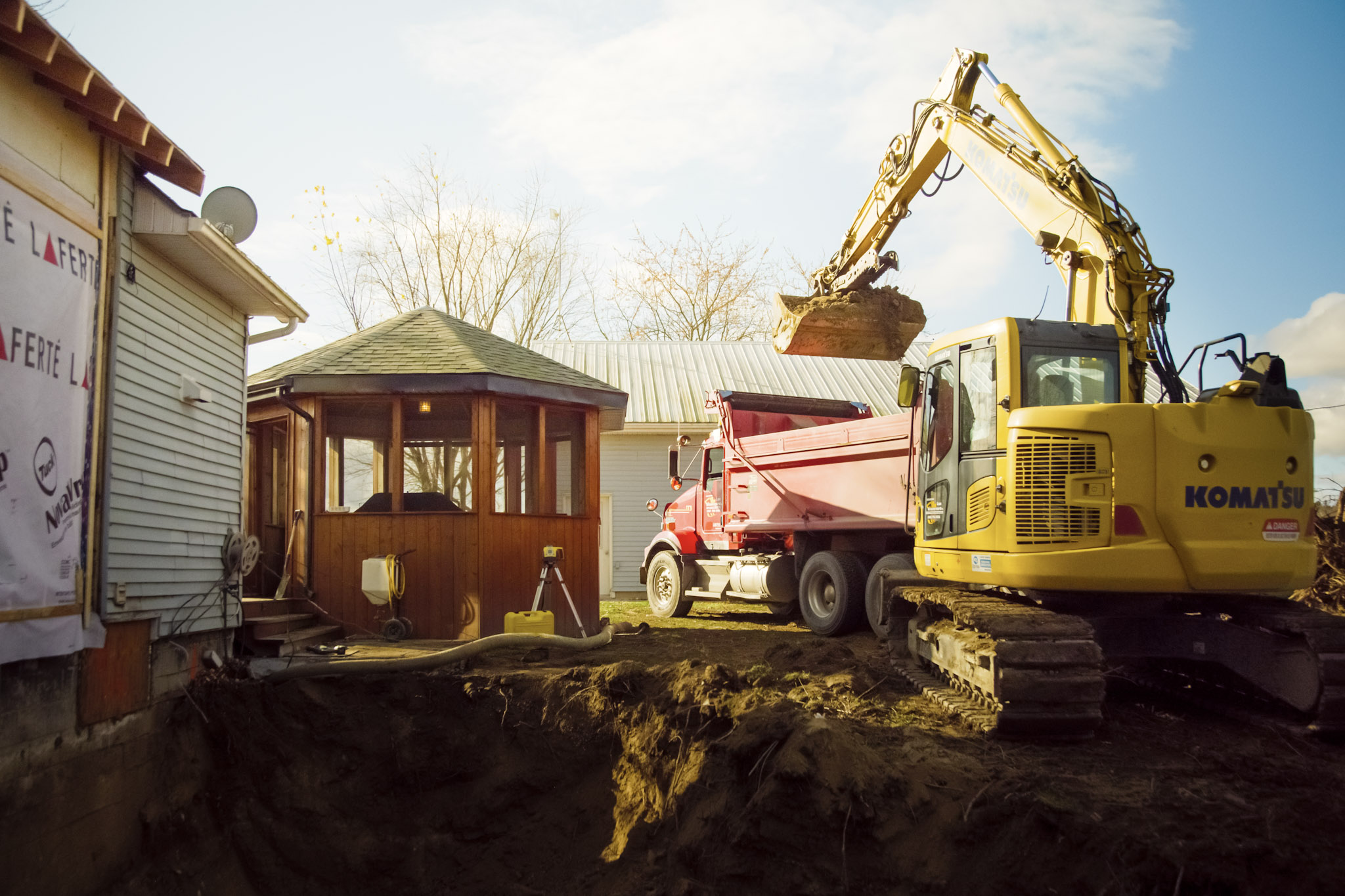 Residential excavation with excavator and dump truck for foundation work and septic installation.