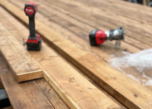 Wooden planks stacked on a workbench with power tools for carpentry work