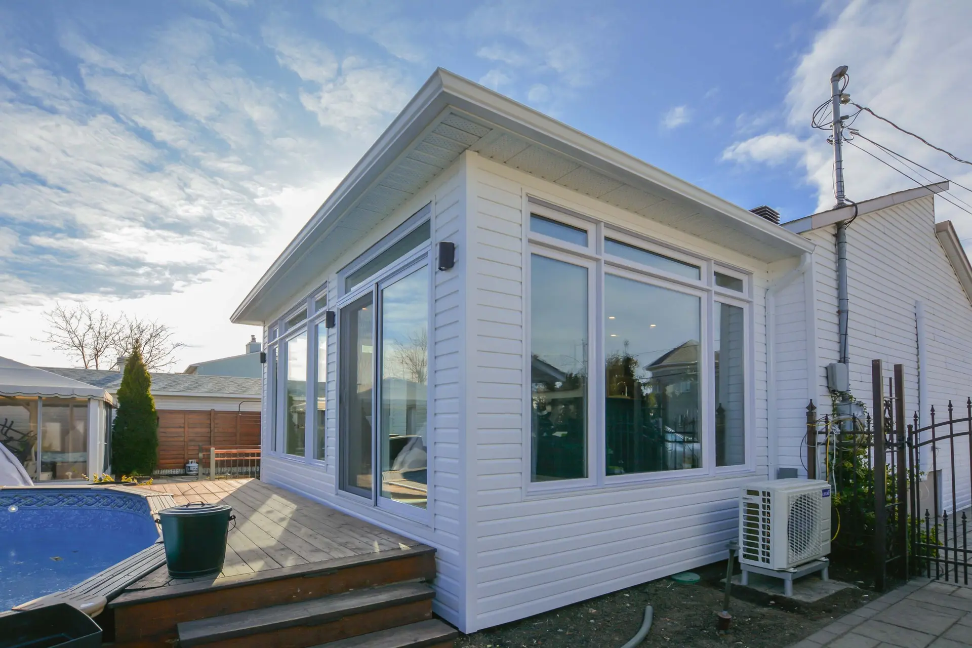 Bright home extension with panoramic windows, wooden deck, and efficient insulation.