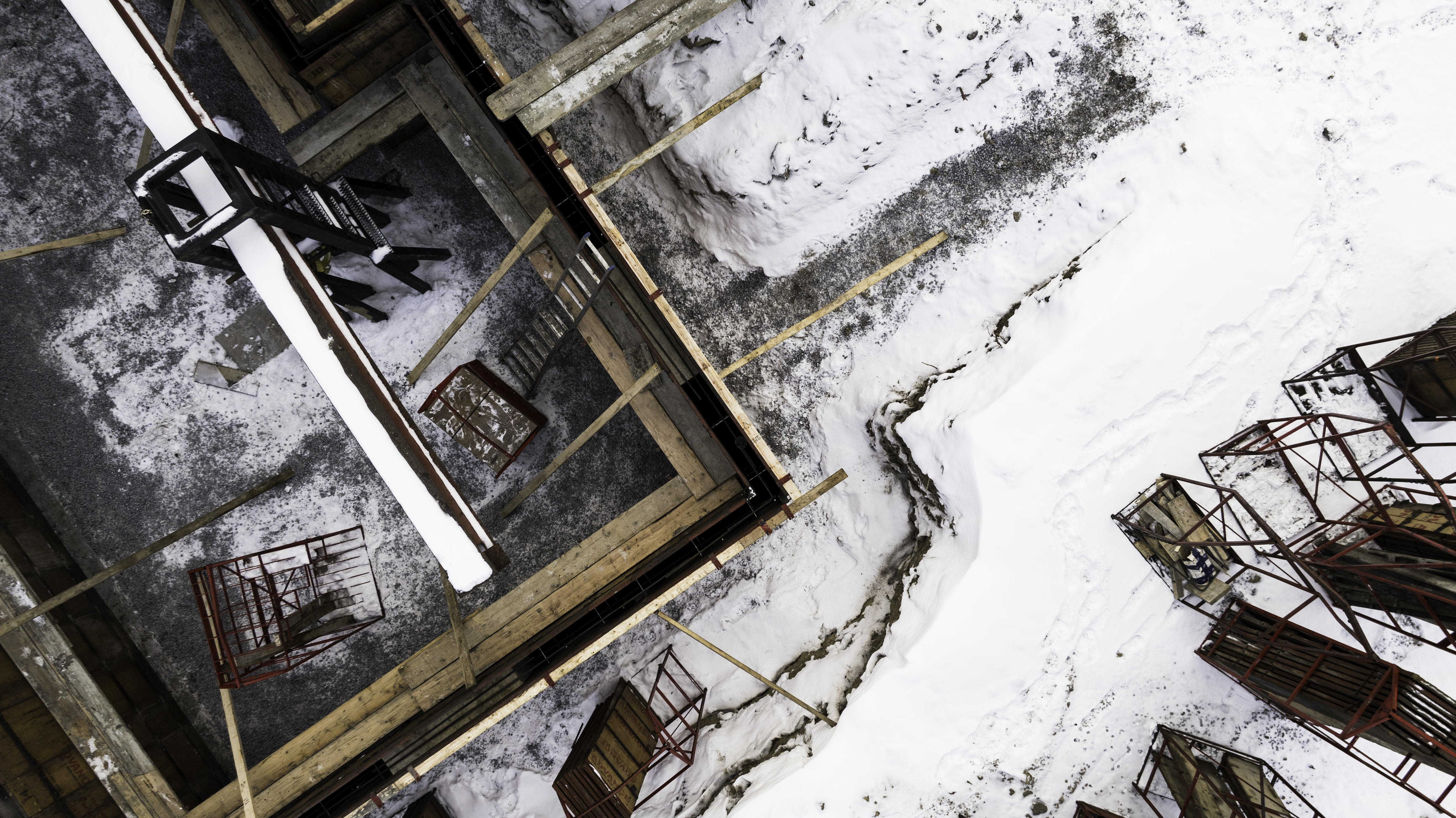 Vue aérienne d’un coffrage de fondation en hiver avec échafaudages et outils de construction dans la neige