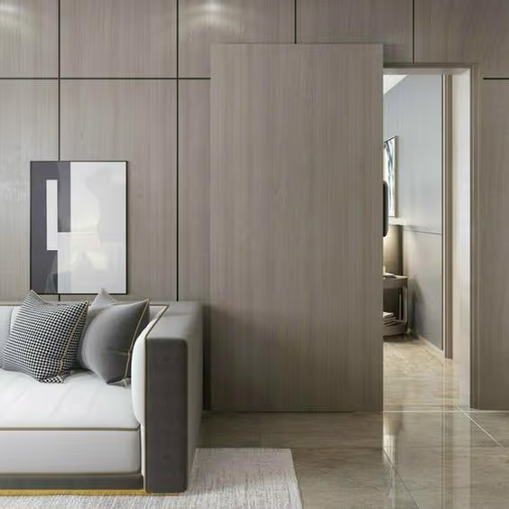 Porte coulissante dissimulée en bois clair intégrée à un mur lambrissé moderne, créant une transition élégante entre le salon et la pièce adjacente.
