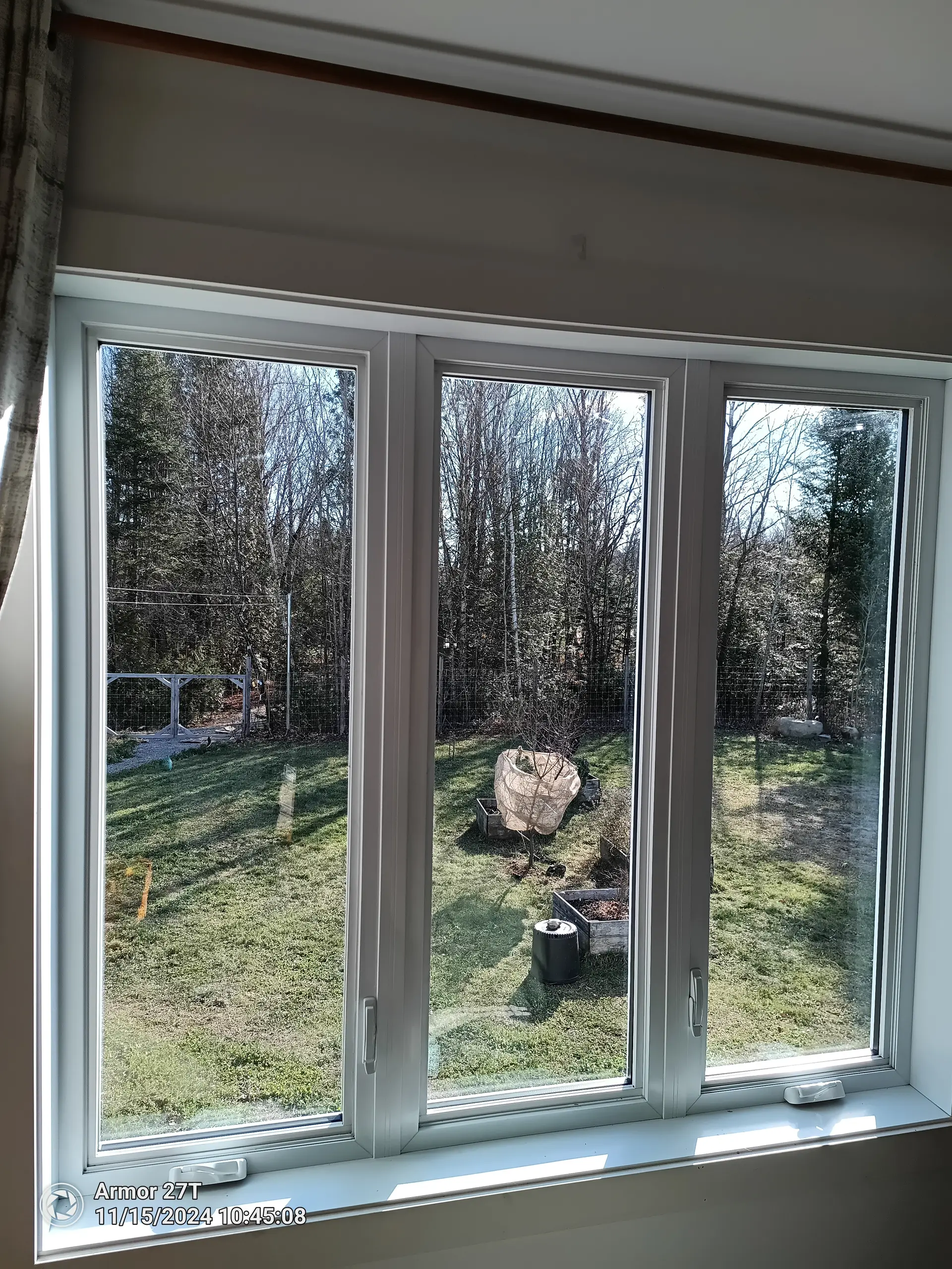Indoor view of a garden through a triple-pane PVC window with white frame