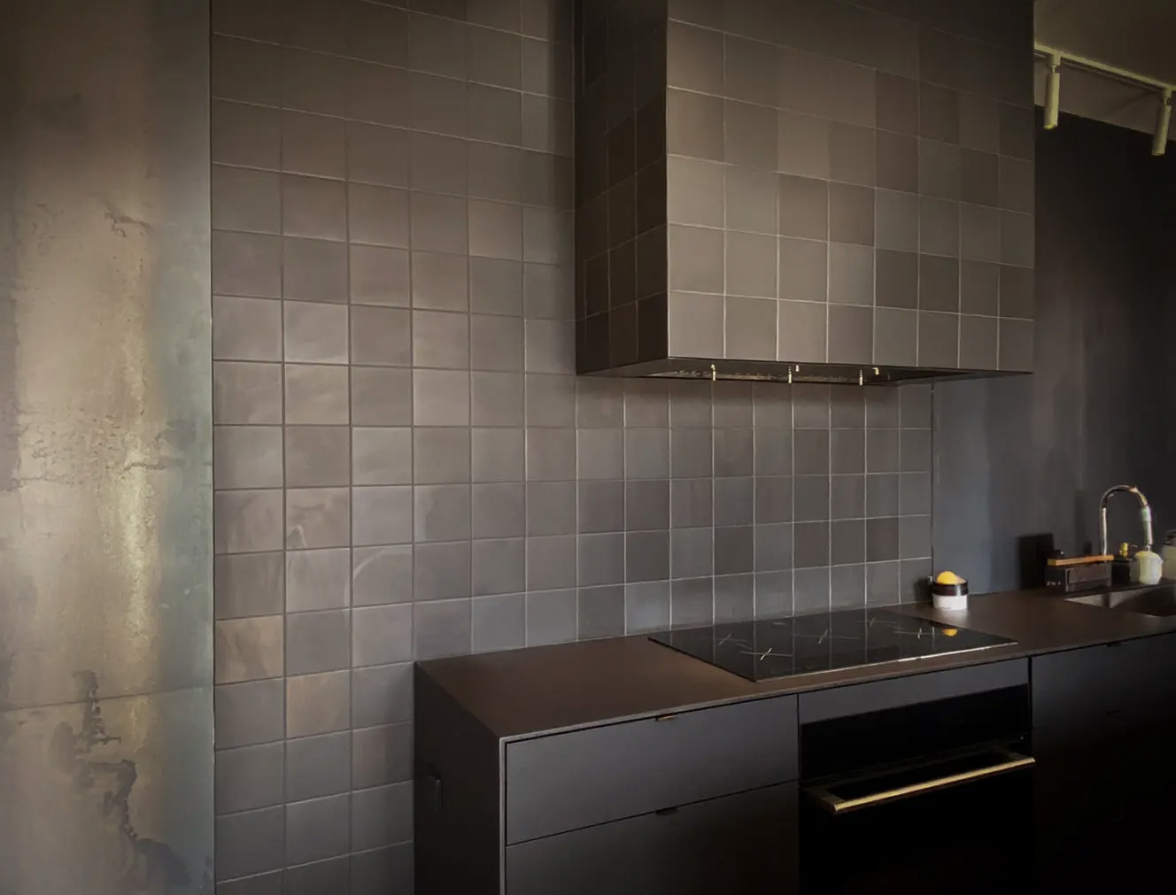 Modern kitchen with matte black ceramic backsplash and hood, sleek countertop and integrated appliances