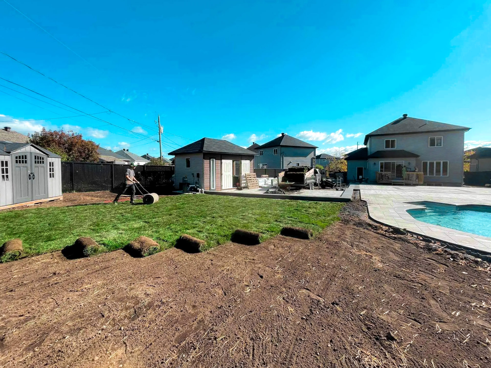 Installation de tourbe dans une cour arrière résidentielle avec piscine creusée, pavé, cabanon et aménagement paysager en cours.