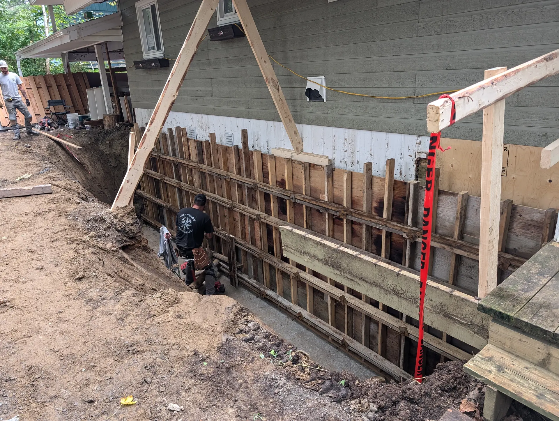 Chantier d’excavation avec coffrage en bois le long d’une fondation de maison pour travaux de structure et de béton