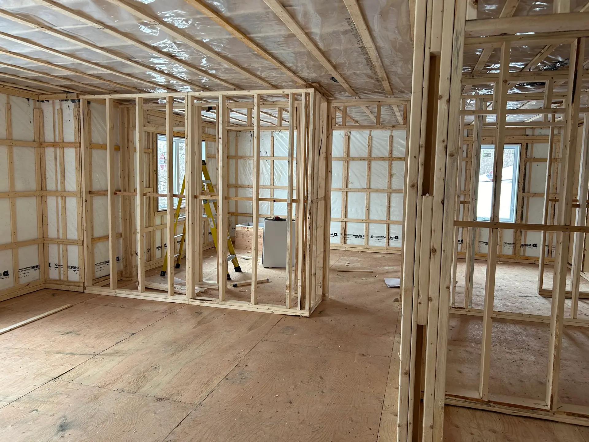 Wooden framework of a house under renovation, with partially built interior walls and a plywood floor.