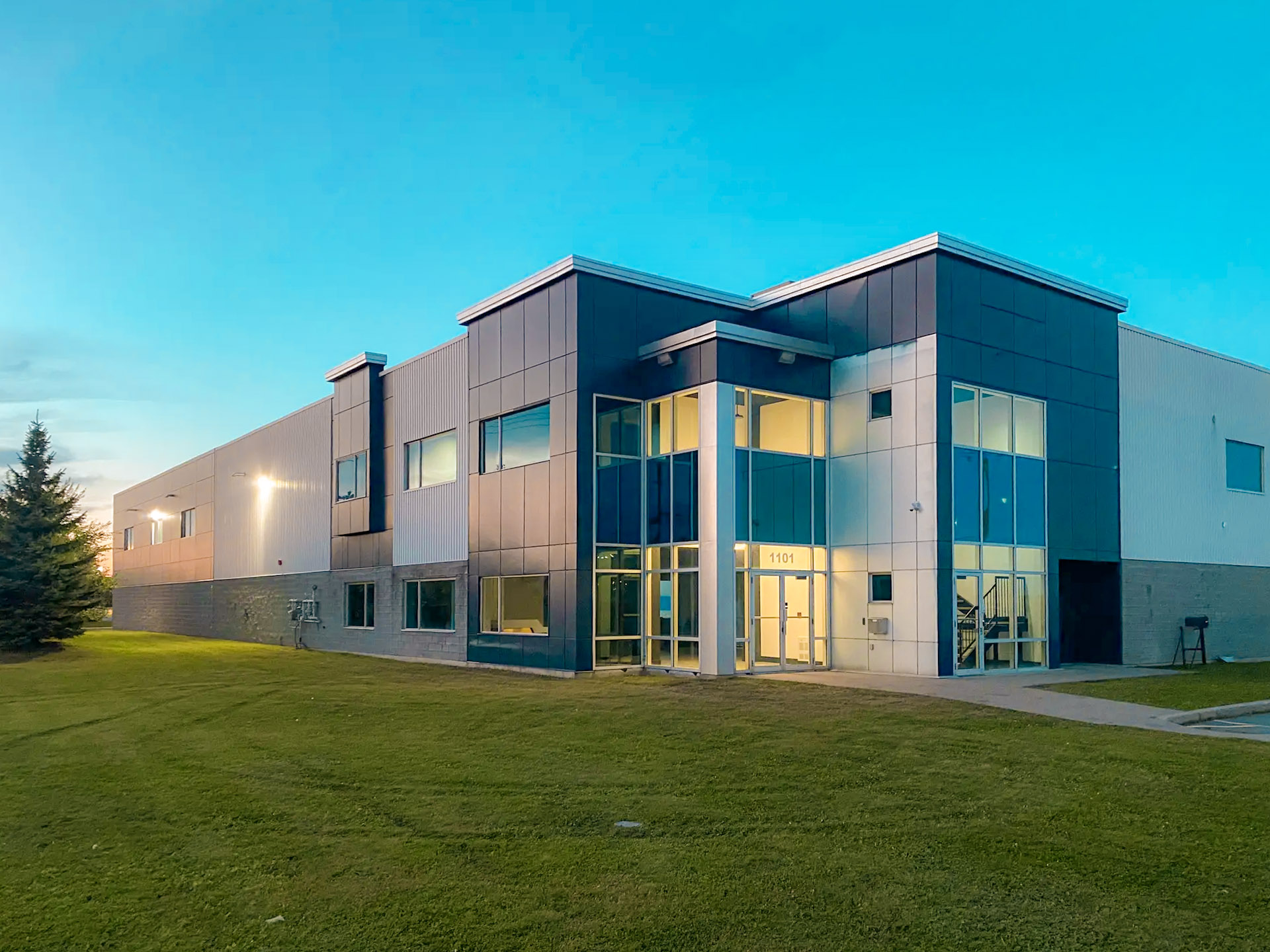 Modern commercial building with glass facade and fiber cement panel exterior cladding at dusk