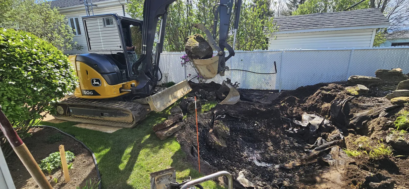 Excavation paysagère avec mini pelle pour retrait de roches et préparation de terrain résidentiel.