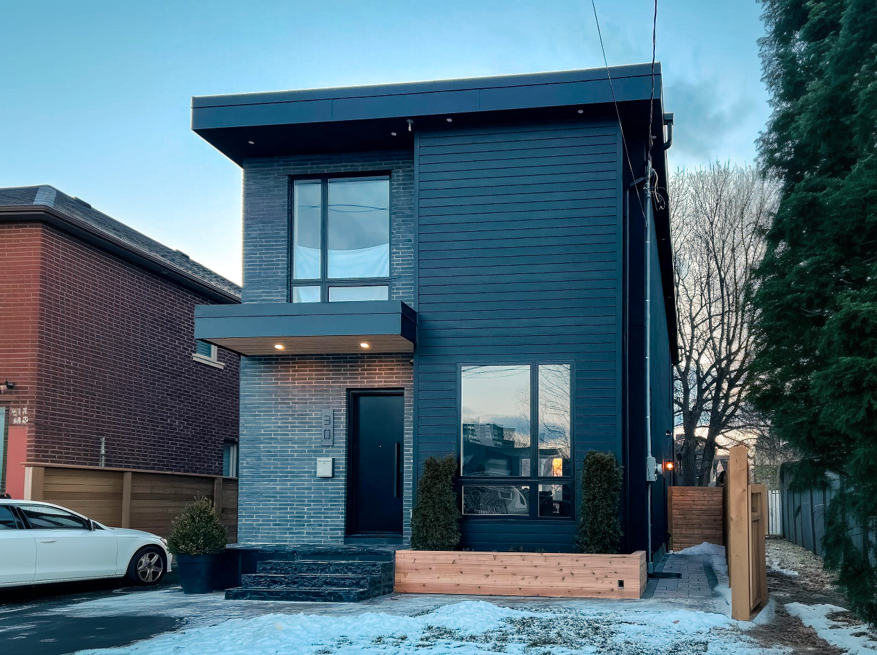 Contemporary house with black facade with mixed wood and brick cladding, modern windows and flat roof in winter