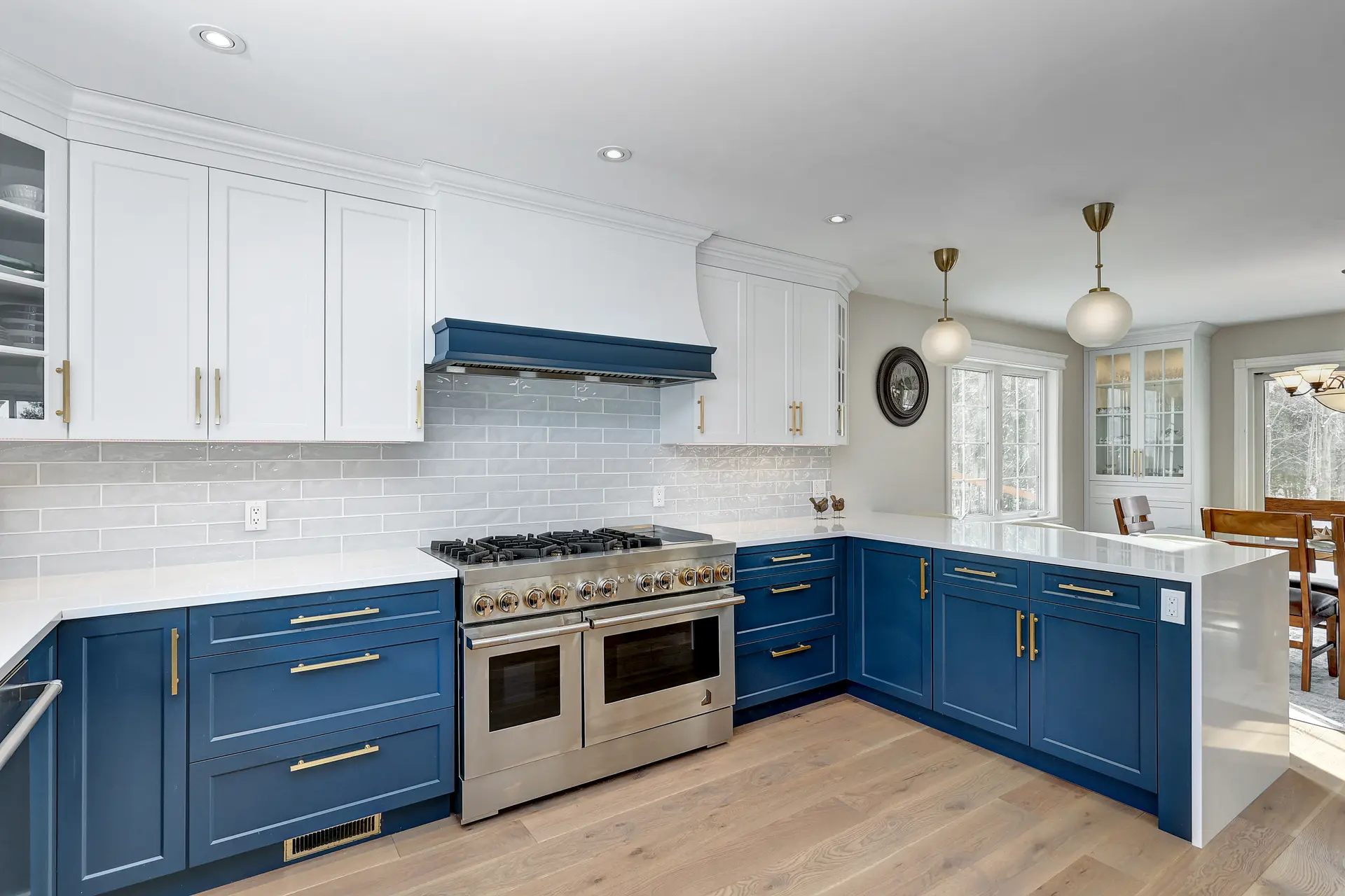 Modern kitchen with blue and white cabinets, quartz countertop, ceramic backsplash and stainless steel stove