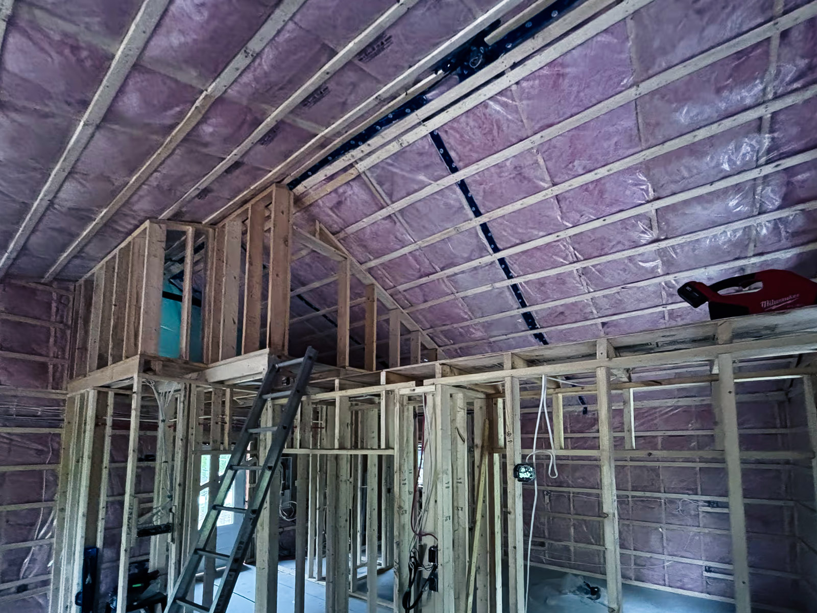 Charpente intérieure en bois avec isolation rose en cours d’installation dans un grenier ou étage d’une maison neuve en construction.