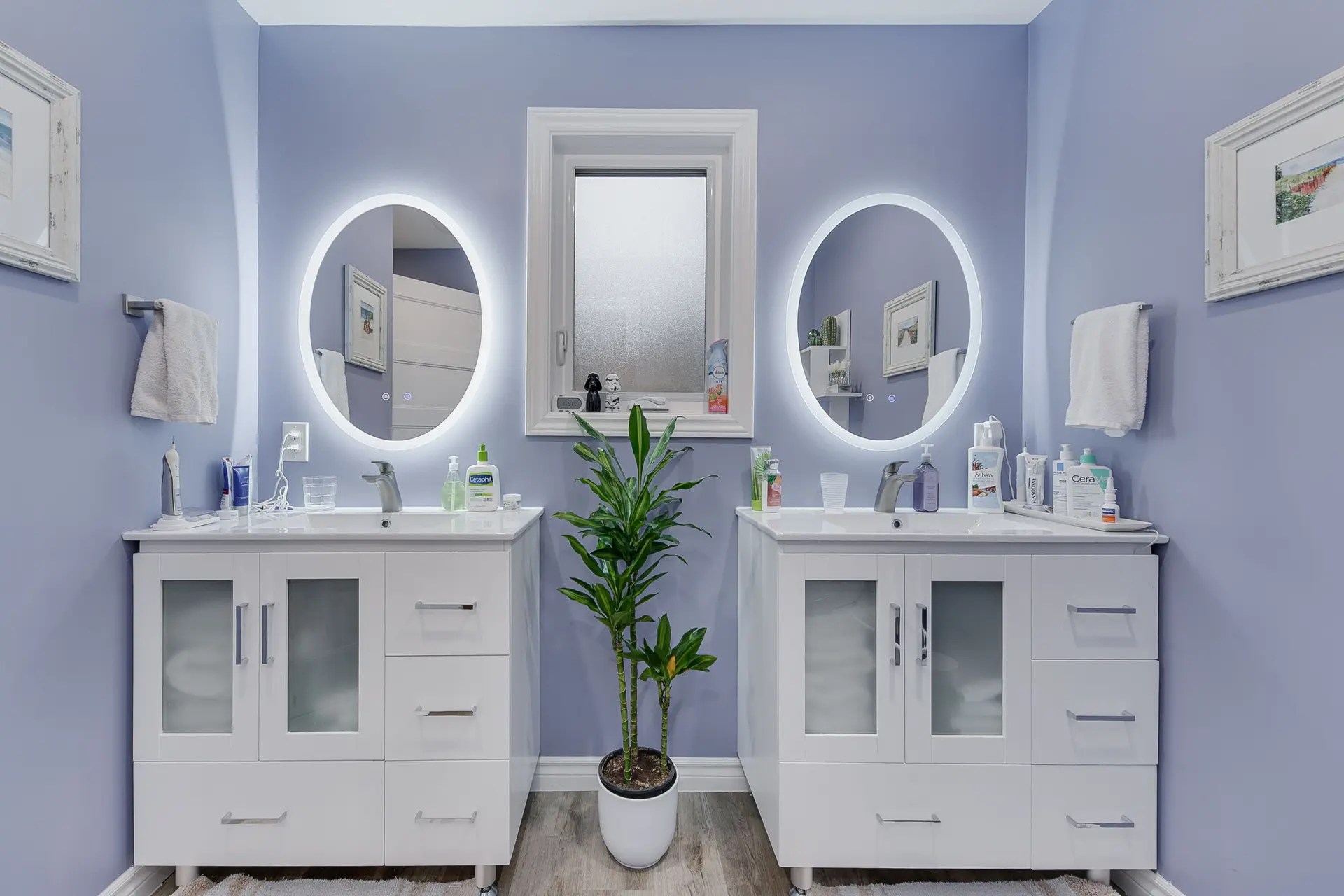 Renovated bathroom with backlit mirrors, double vanity, and modern lighting, combining contemporary design and functionality.