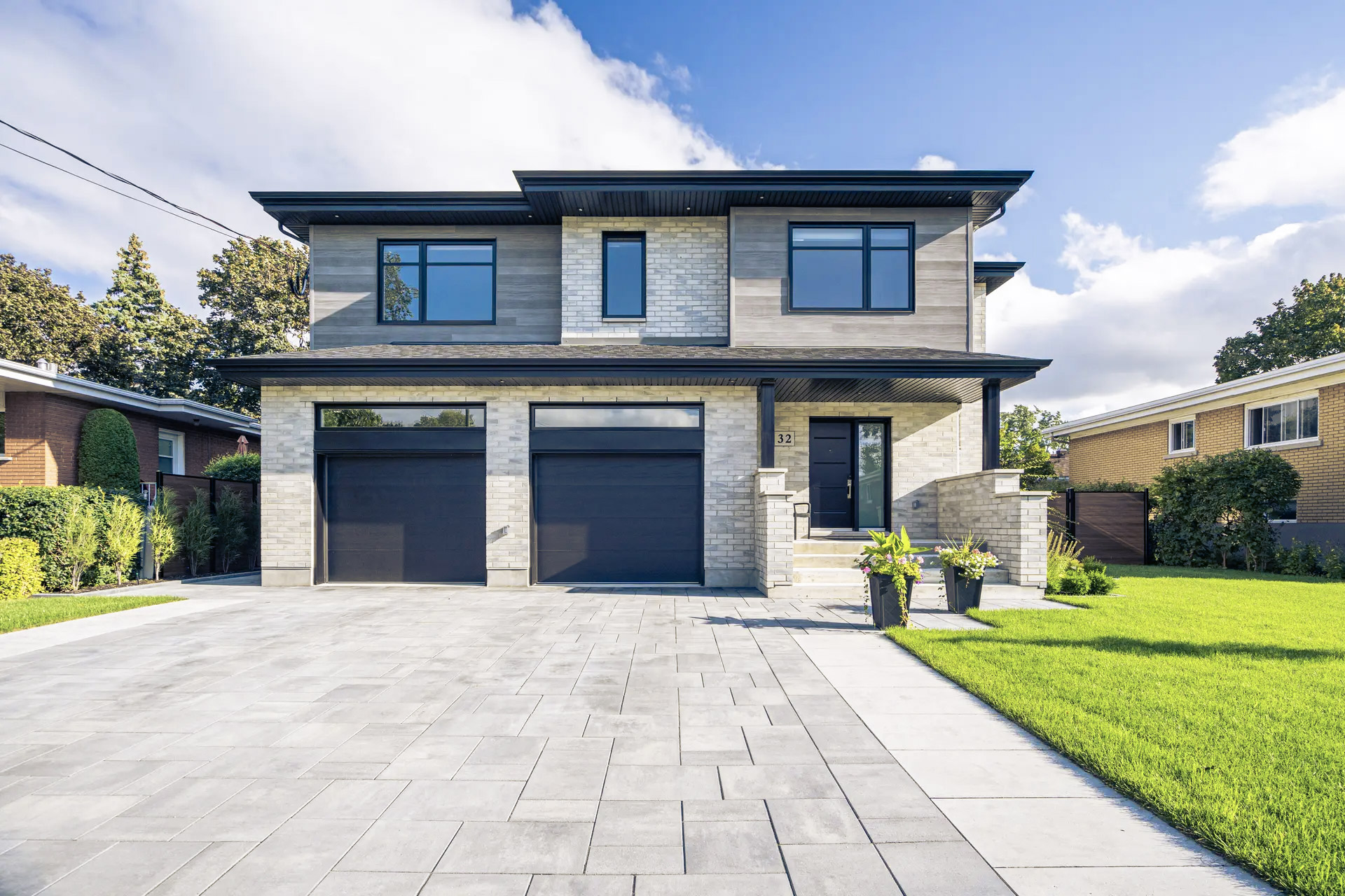 Modern house with brick facade, double garage and paving stones in a residential area.