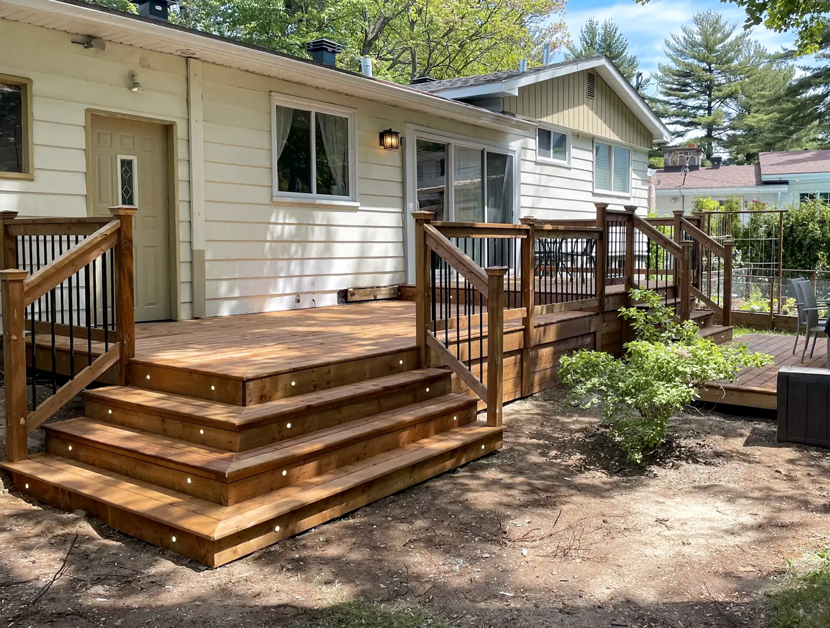 Rear extension of a typical bungalow with new wooden terrace and exterior access, in a leafy residential suburb.