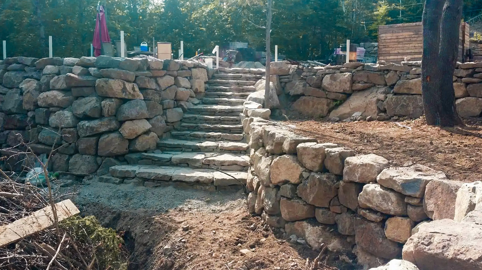Exterior staircase in natural stone surrounded by rustic stone retaining walls