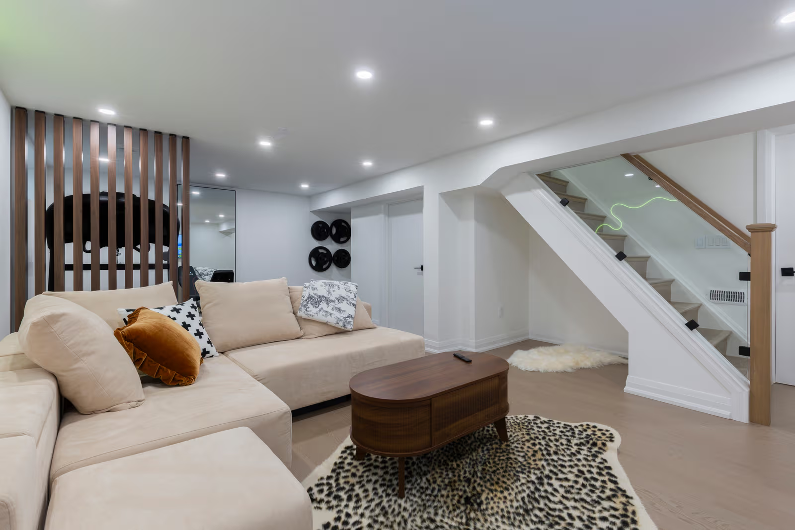 Renovated basement living room with sectional sofa, glass staircase, recessed lighting and contemporary decor