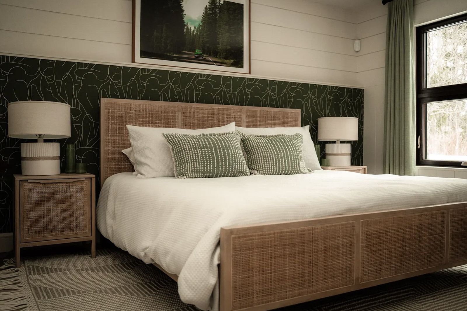 Cozy bedroom with woven wood bed, green accent wall and natural decor.