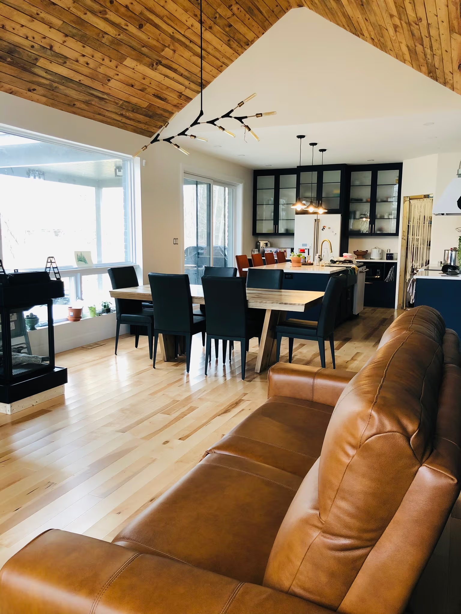 Cuisine moderne ouverte avec salle à manger, plafond en bois chaleureux, grande fenestration et mobilier contemporain